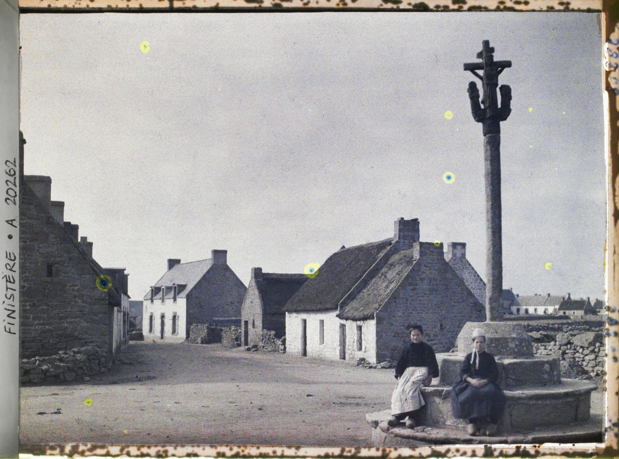 Image représentant Deux femmes dont l'une porte une coiffe traditionnelle, devant un calvaire