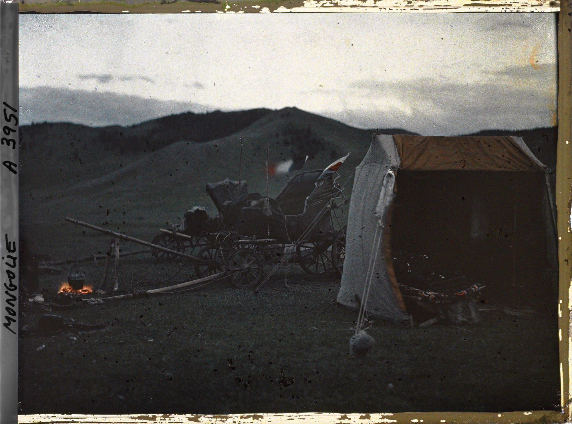 Image représentant La tente de l'opérateur et les deux voitures dételées près d'un feu destiné sans doute à la cuisson du repas