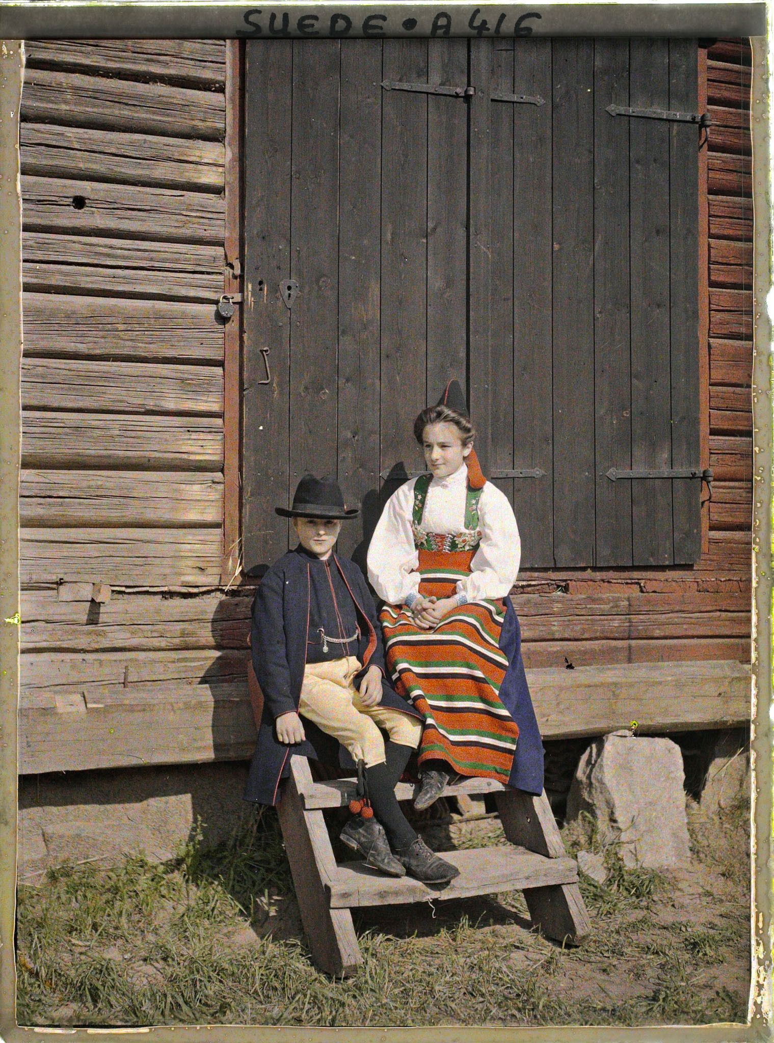 Image représentant Jeune garçon et femme assis devant la porte d'une grange