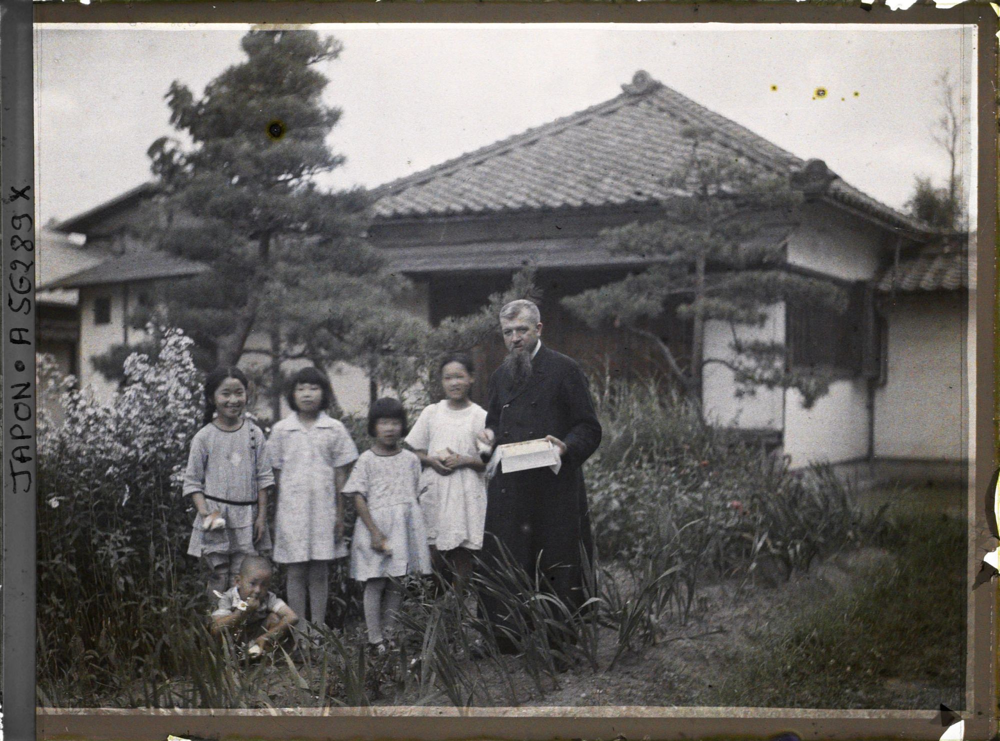 Image représentant Le père Cesselin, missionnaire français, entouré d'un groupe d'enfants vêtus à l'occidentale