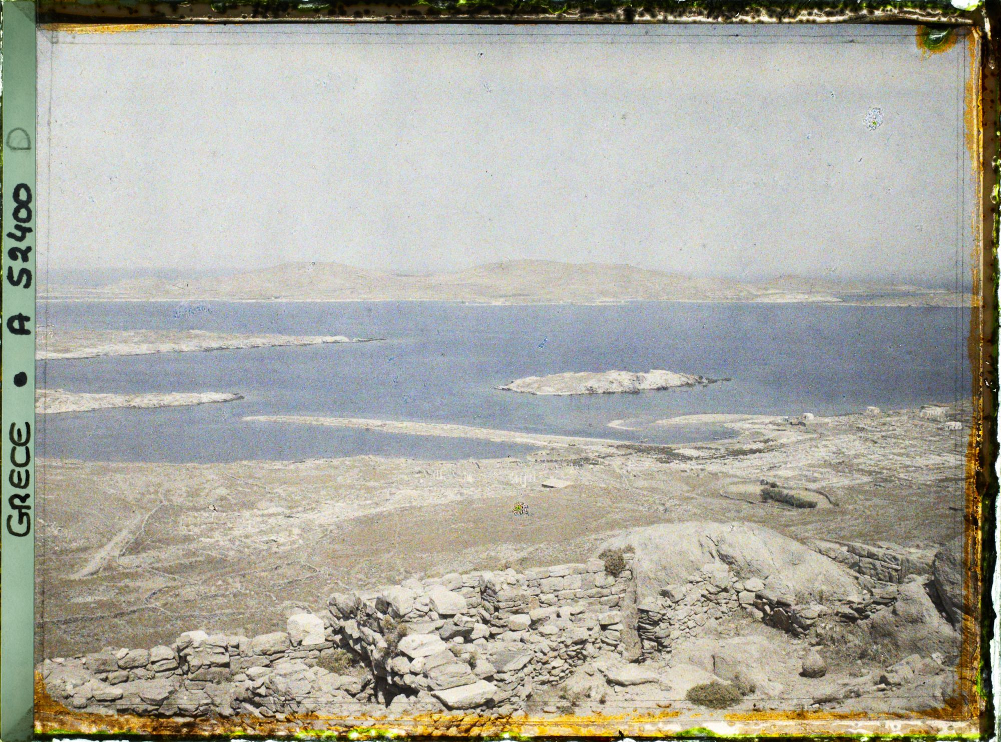 Image représentant Panorama depuis le mont Cynthe en direction de l'ouest, la ville basse et le port (entre les deux bras de terre). Au fond, l'Ile de Syros