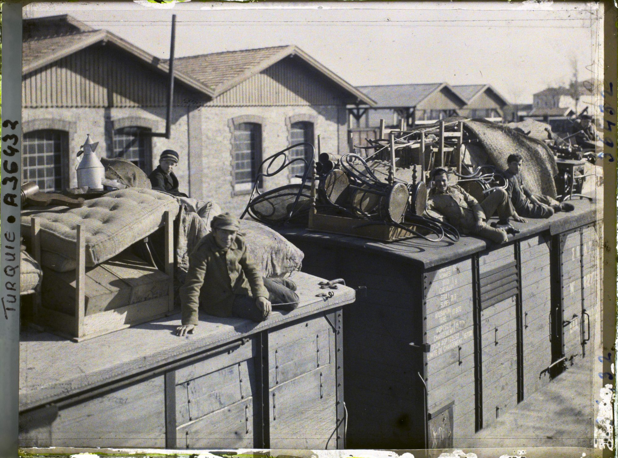 Image représentant Grecs quittant la ville sur le toit d'un train chargé de mobilier, de matelas et d'objets divers