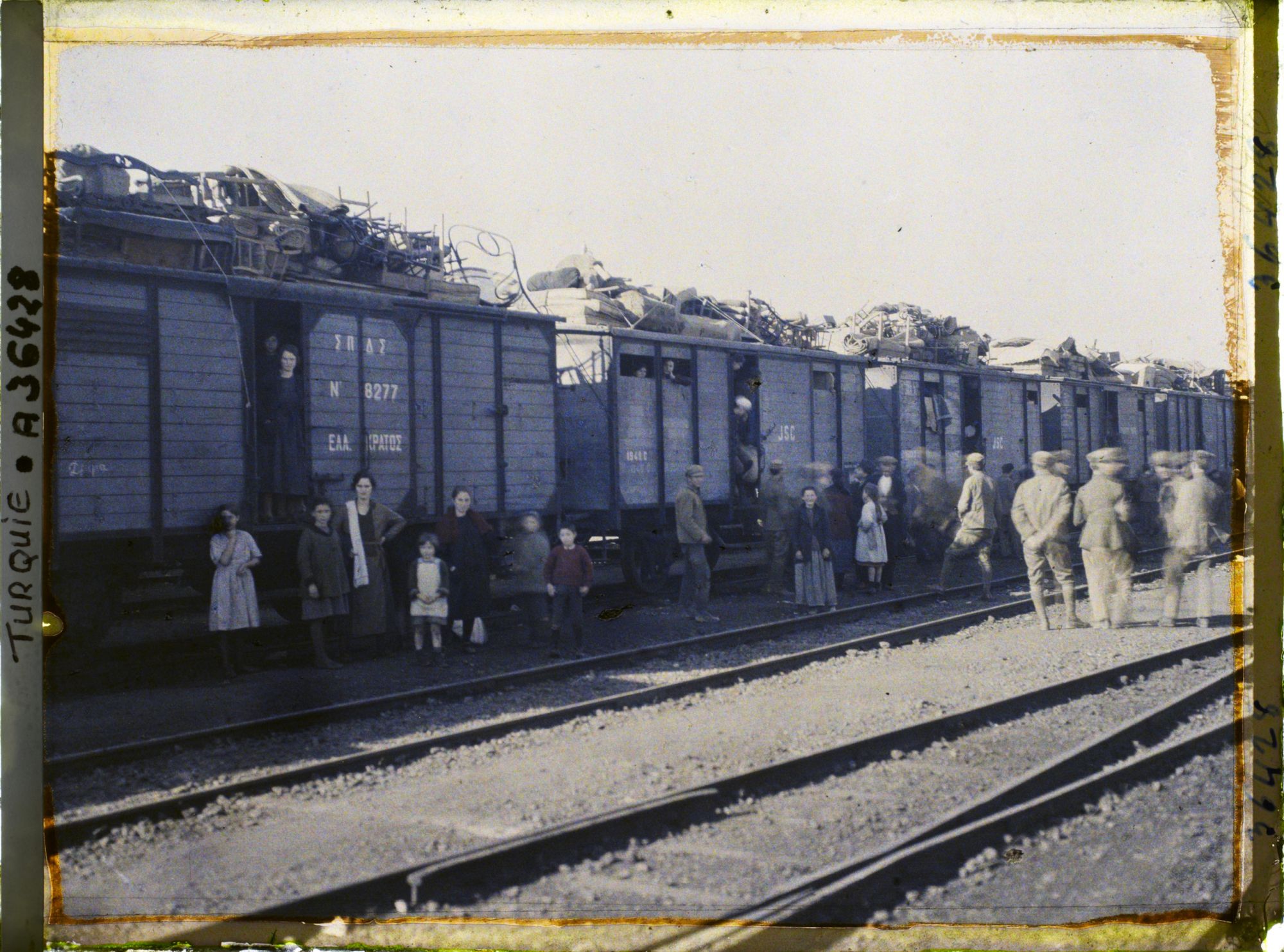 Image représentant Grecs quittant la ville, au pied d'un train chargé de mobilier