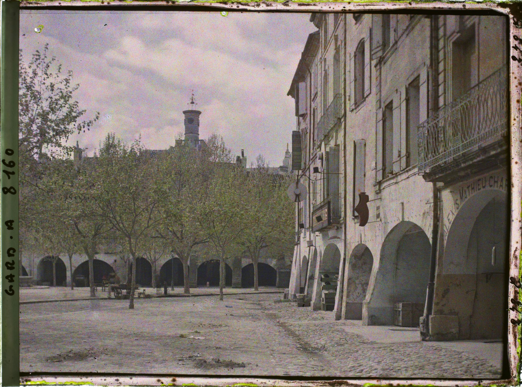 Image représentant Les arcades de la place de la République (devenue place aux Herbes) avec au second plan la tour de l'église Saint-Etienne