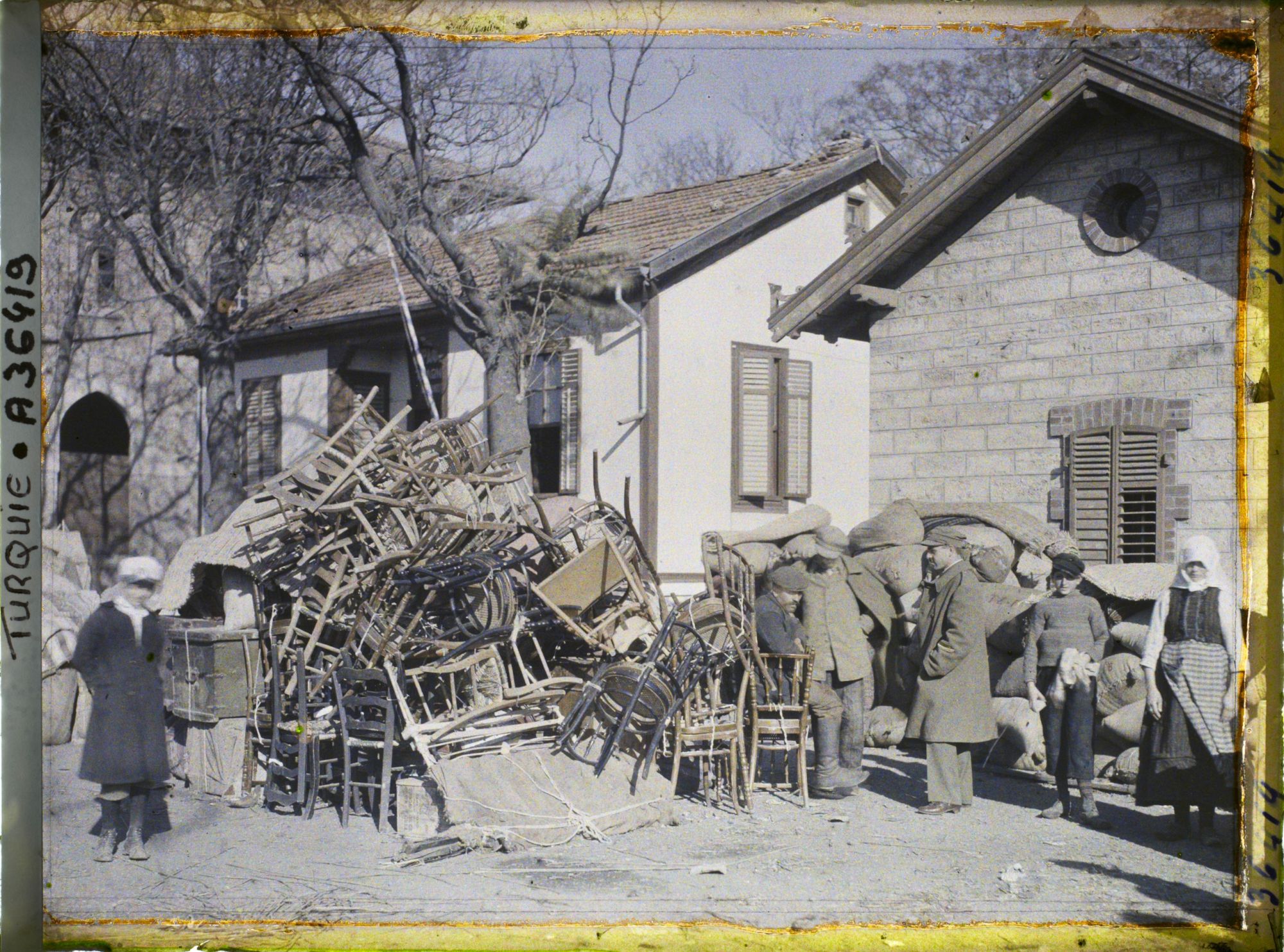 Image représentant Grecs quittant la ville près d'un amas de mobiliers, aux abords de la gare