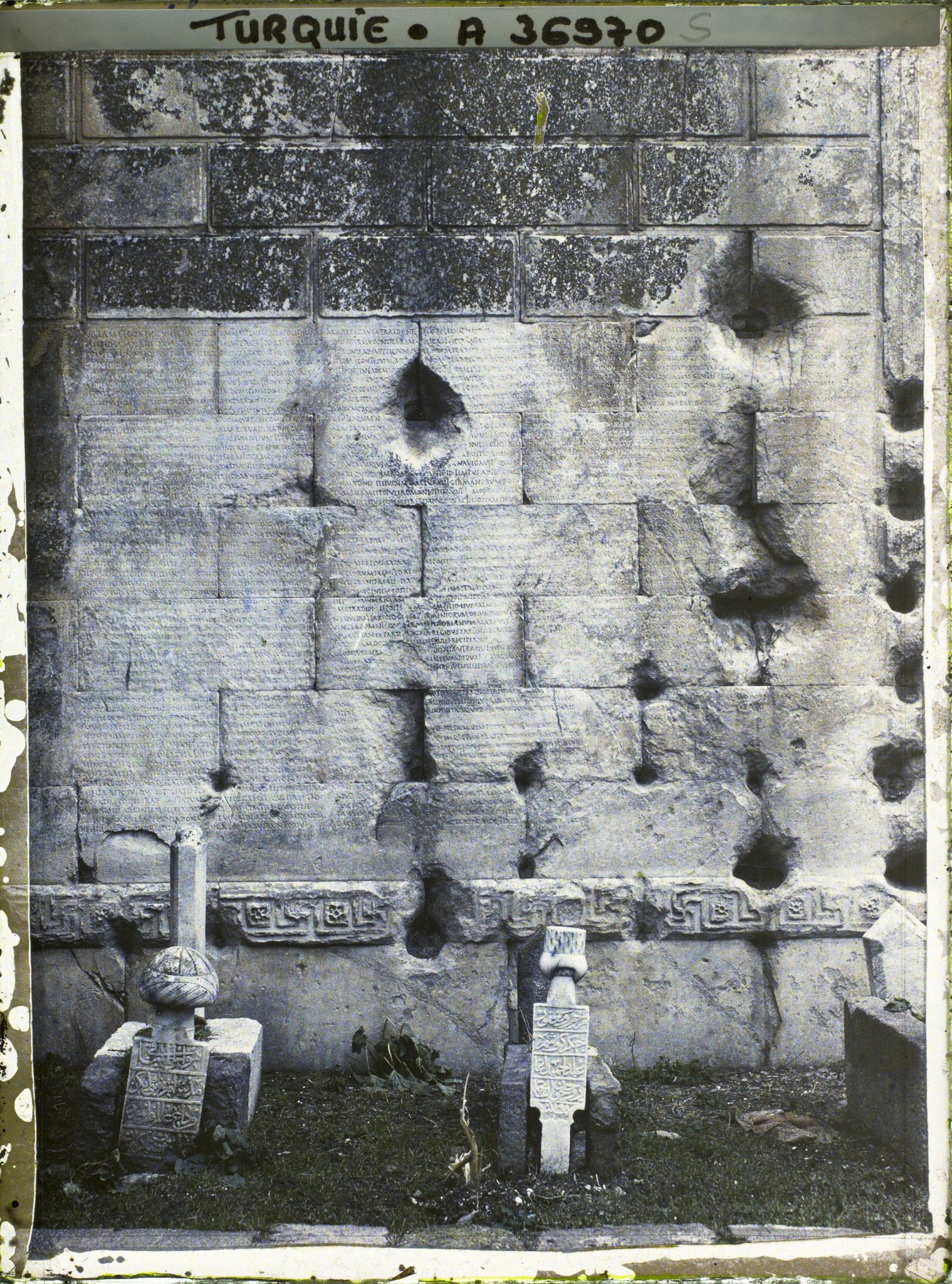 Image représentant Textes en latin gravés sur un mur du temple d'Auguste et de Rome , (testament politique d'Auguste). Au premier plan, tombes musulmanes (le temple fut transformé en mosquée)