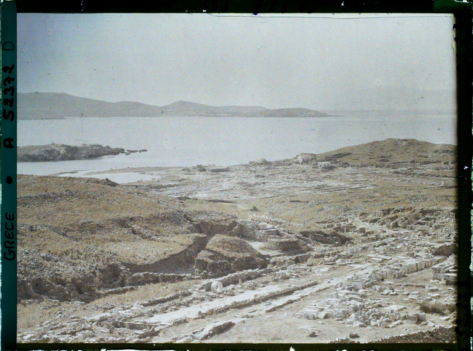 Image représentant Panorama vers les ruines de la ville antique (haute et basse) et la mer depuis l'Antre du Cinthe sur le versant occidental du mont Cinthe (au fond, l'Ile de Syros)