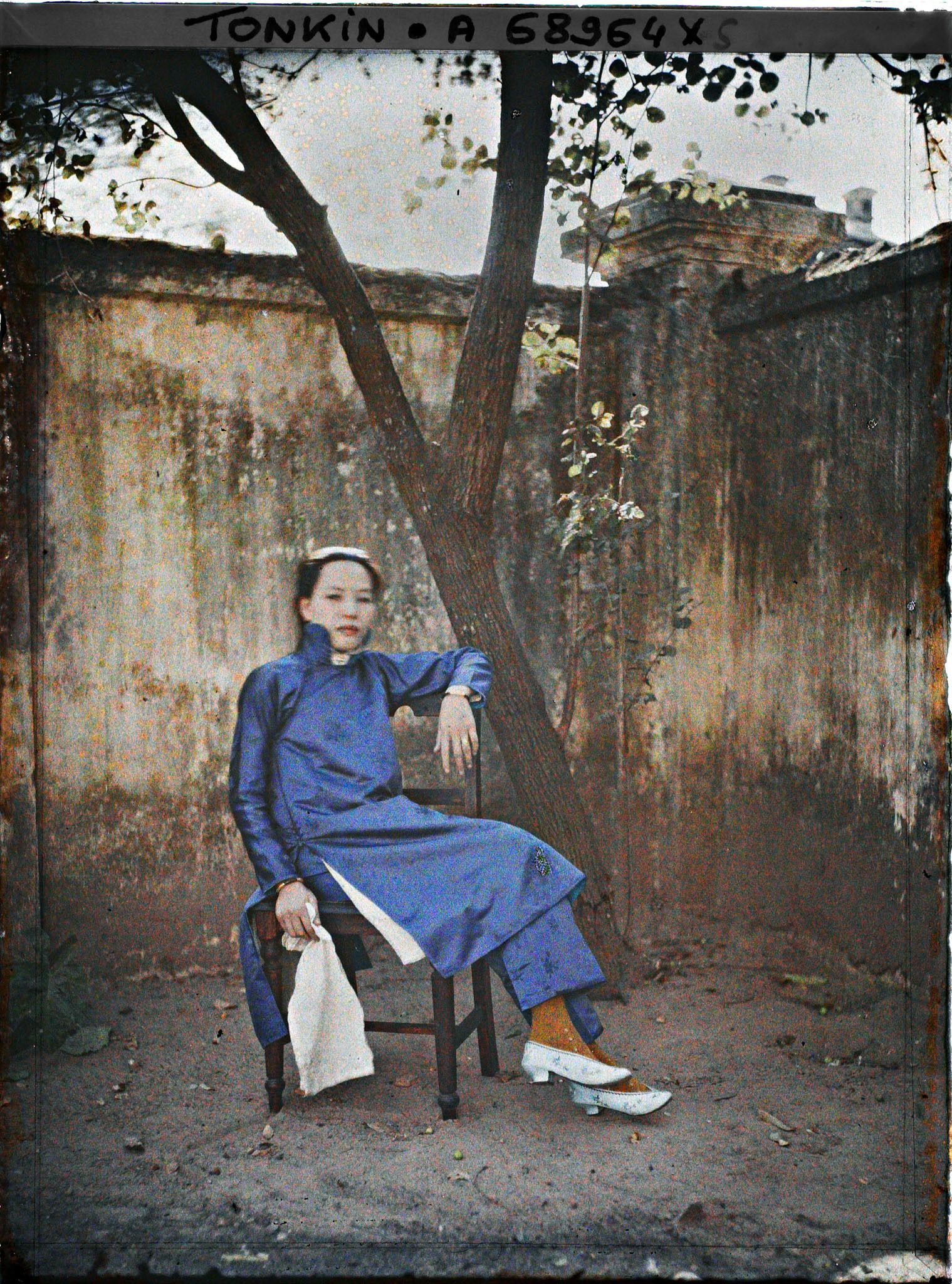 Image représentant Une métisse chinoise assise sur une chaise, de trois quarts, dans un angle de cour
