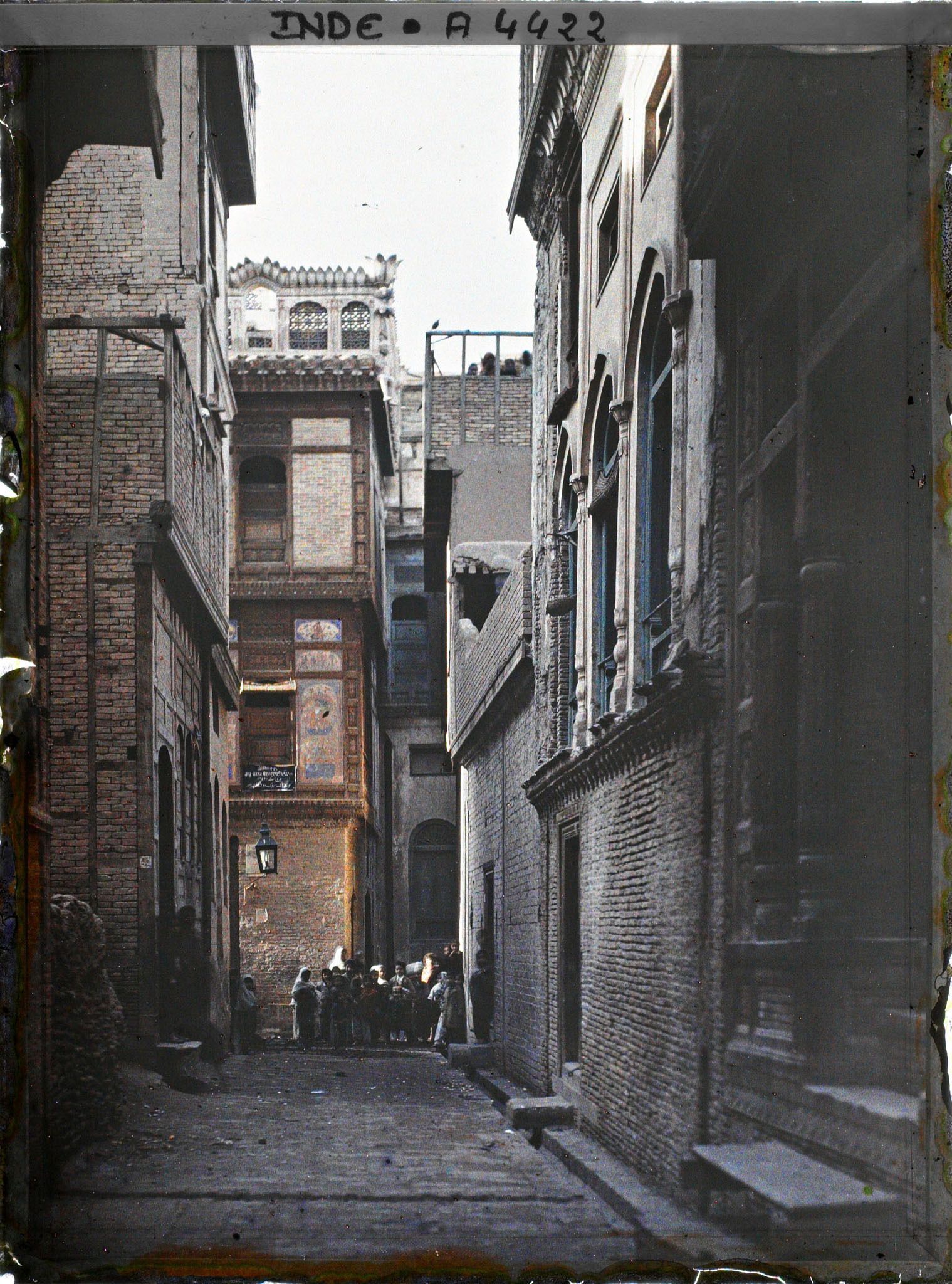 Image représentant Une rue : à l'arrière-plan, groupe de femmes et d'enfants