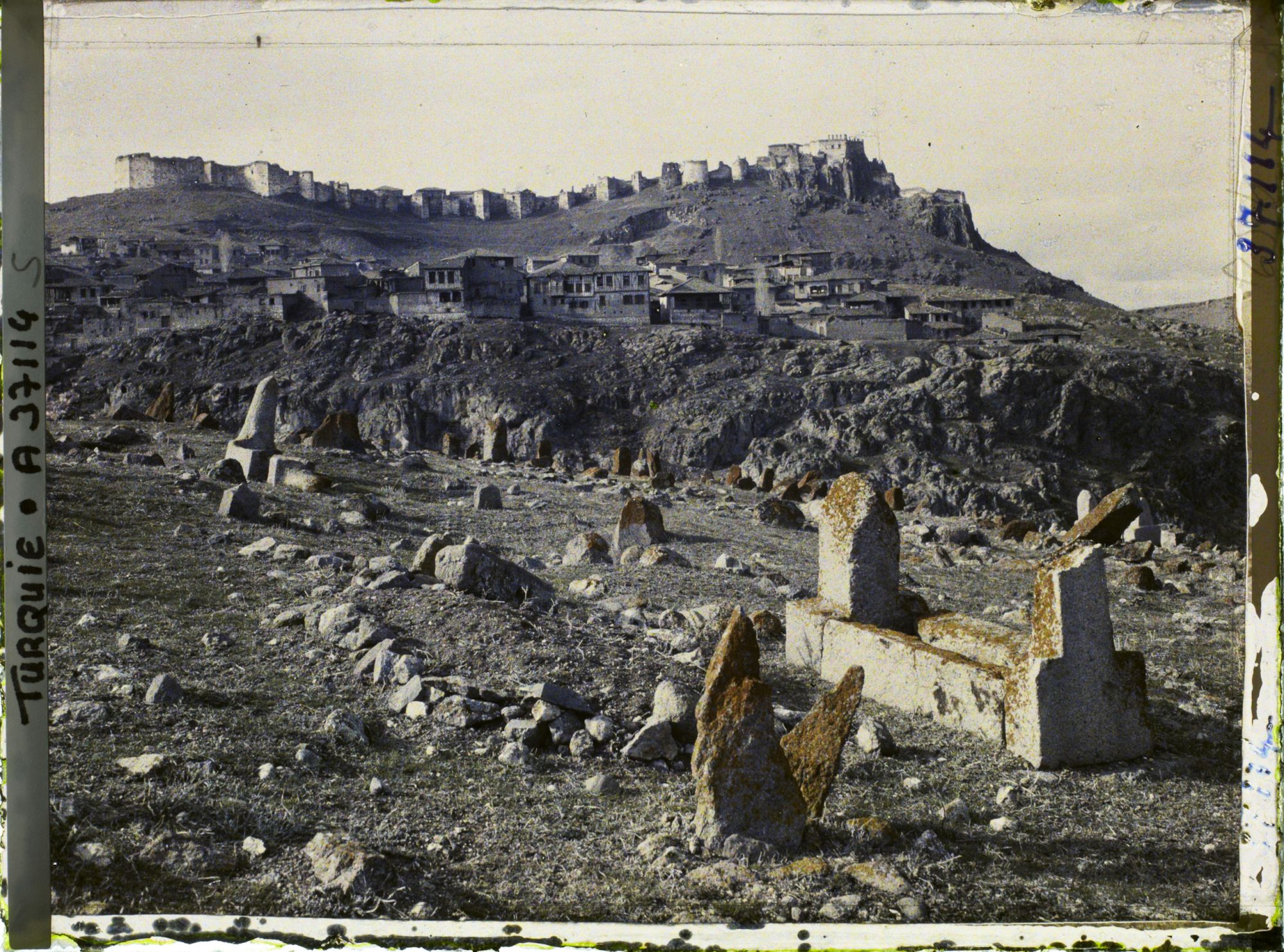 Image représentant Vers la ville surmontée de sa citadelle. Au premier plan, pierres tombales et l'un des cimetières entourant la ville