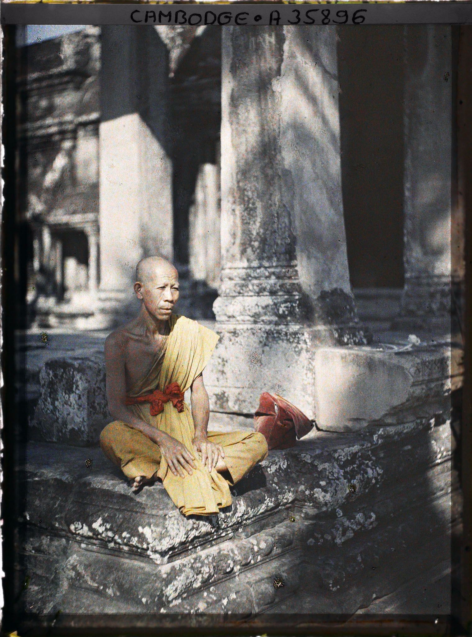 Image représentant Un bonze âgé, assis dans une galerie du préau cruciforme