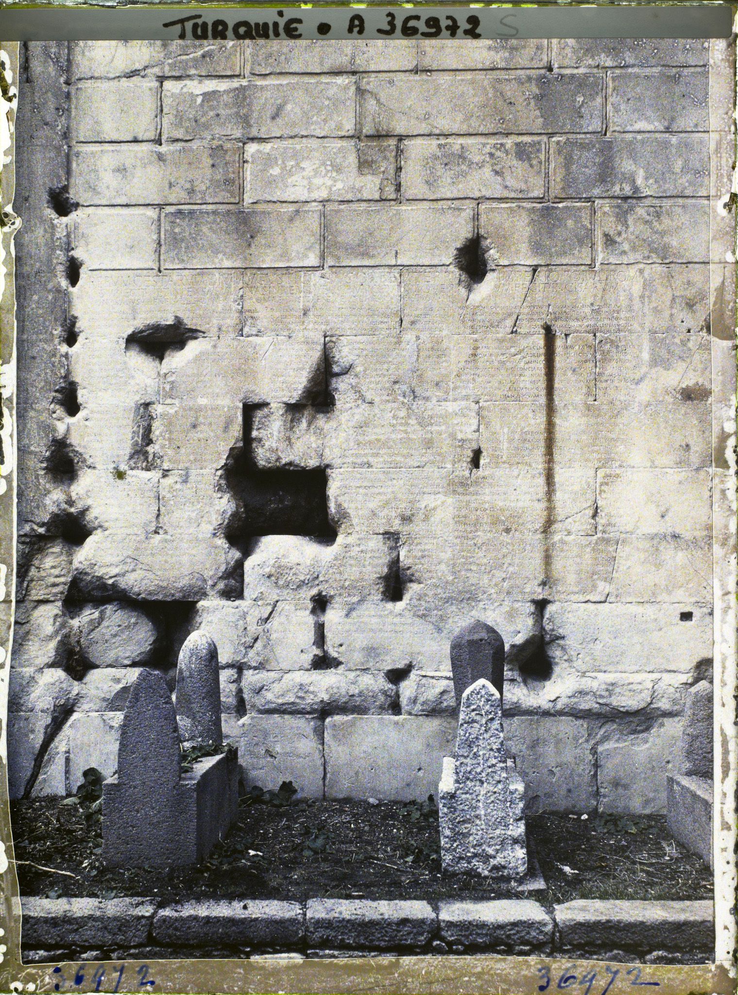 Image représentant Textes en latin gravés sur un mur du temple d'Auguste et de Rome, (testament politique d'Auguste). Au premier plan, tombes musulmanes (le temple fut tranformé en mosquée)