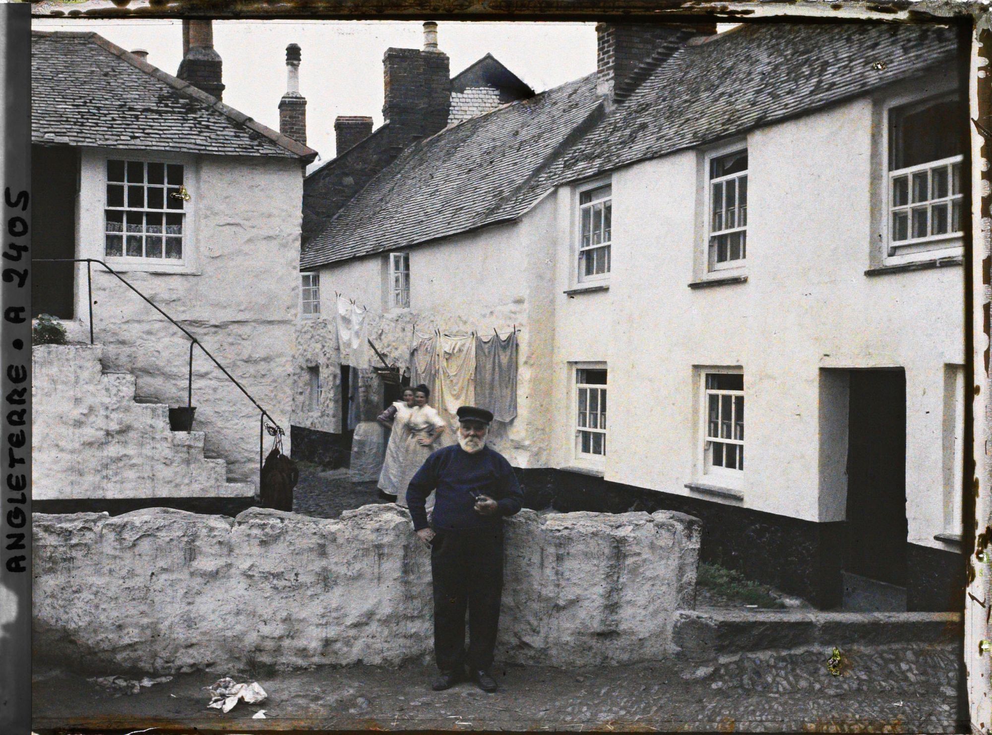 Image représentant Un pêcheur fumant la pipe posant devant des habitations