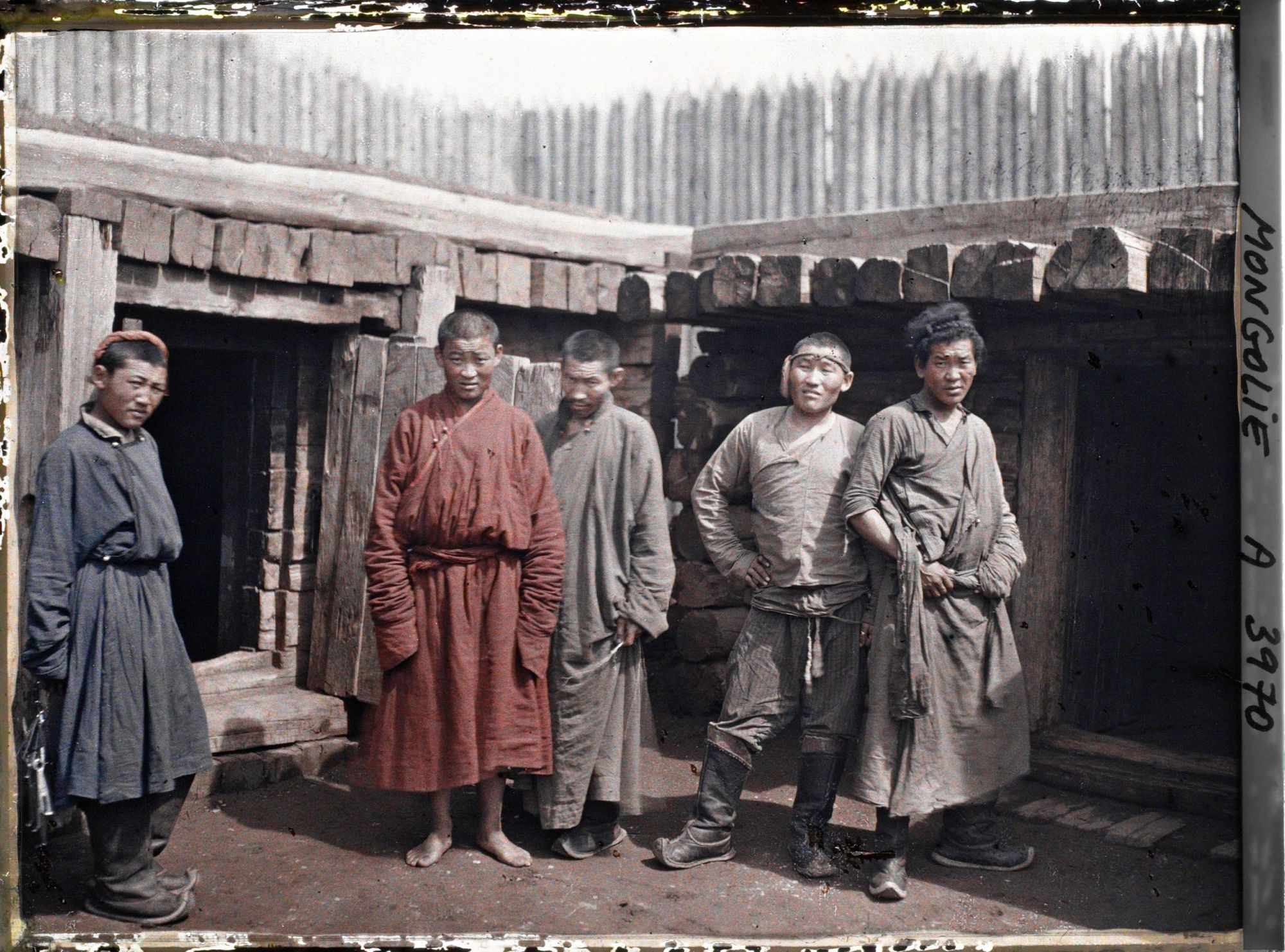 Image représentant Gardiens, détenus parmi lesquels peut-être un jeune lama près d'une cellule, dans la cour de la prison