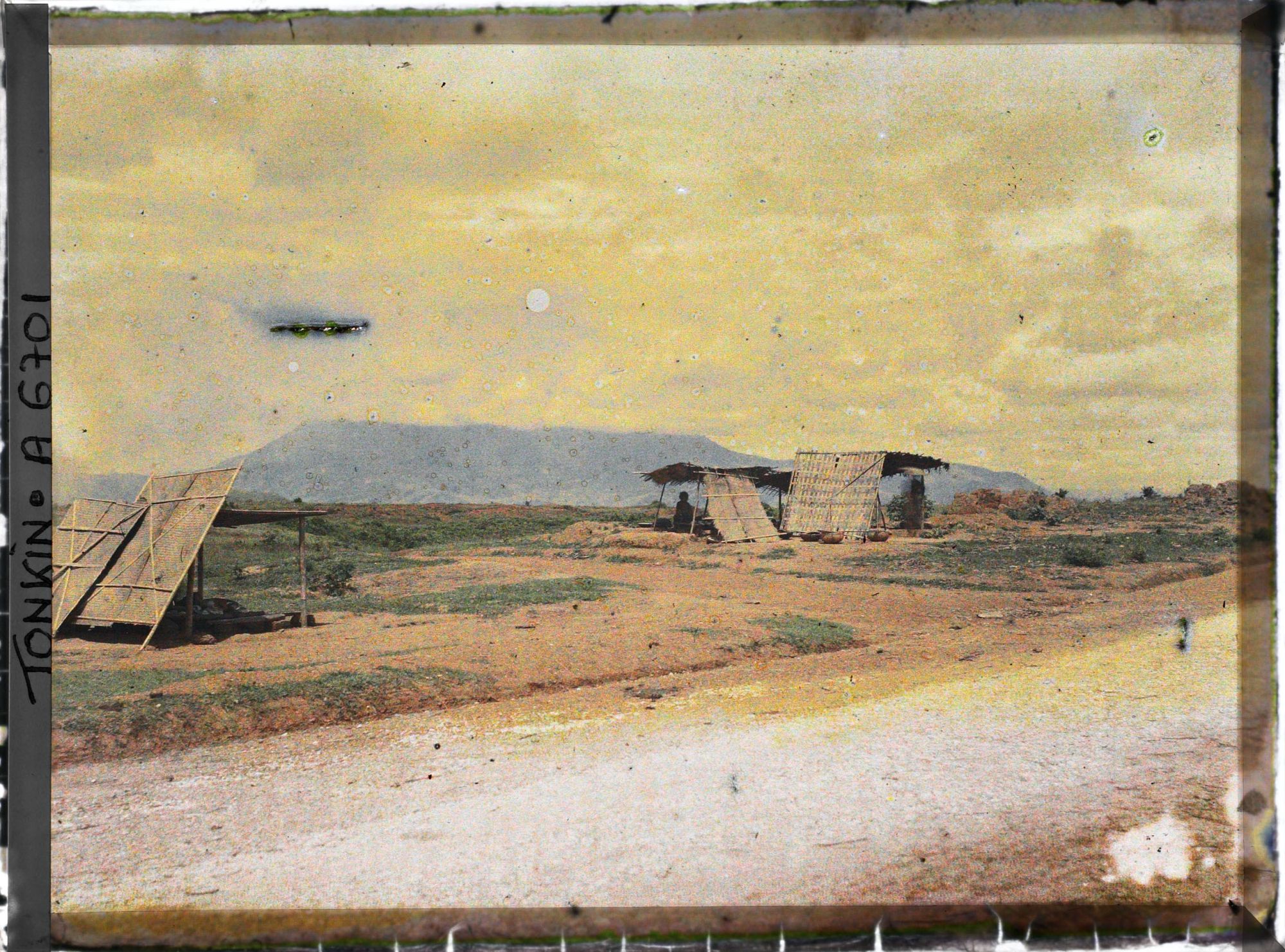 Image représentant Des marchands ou des petits restaurants en plein air, installés sous des abris de paille, au bord du chemin