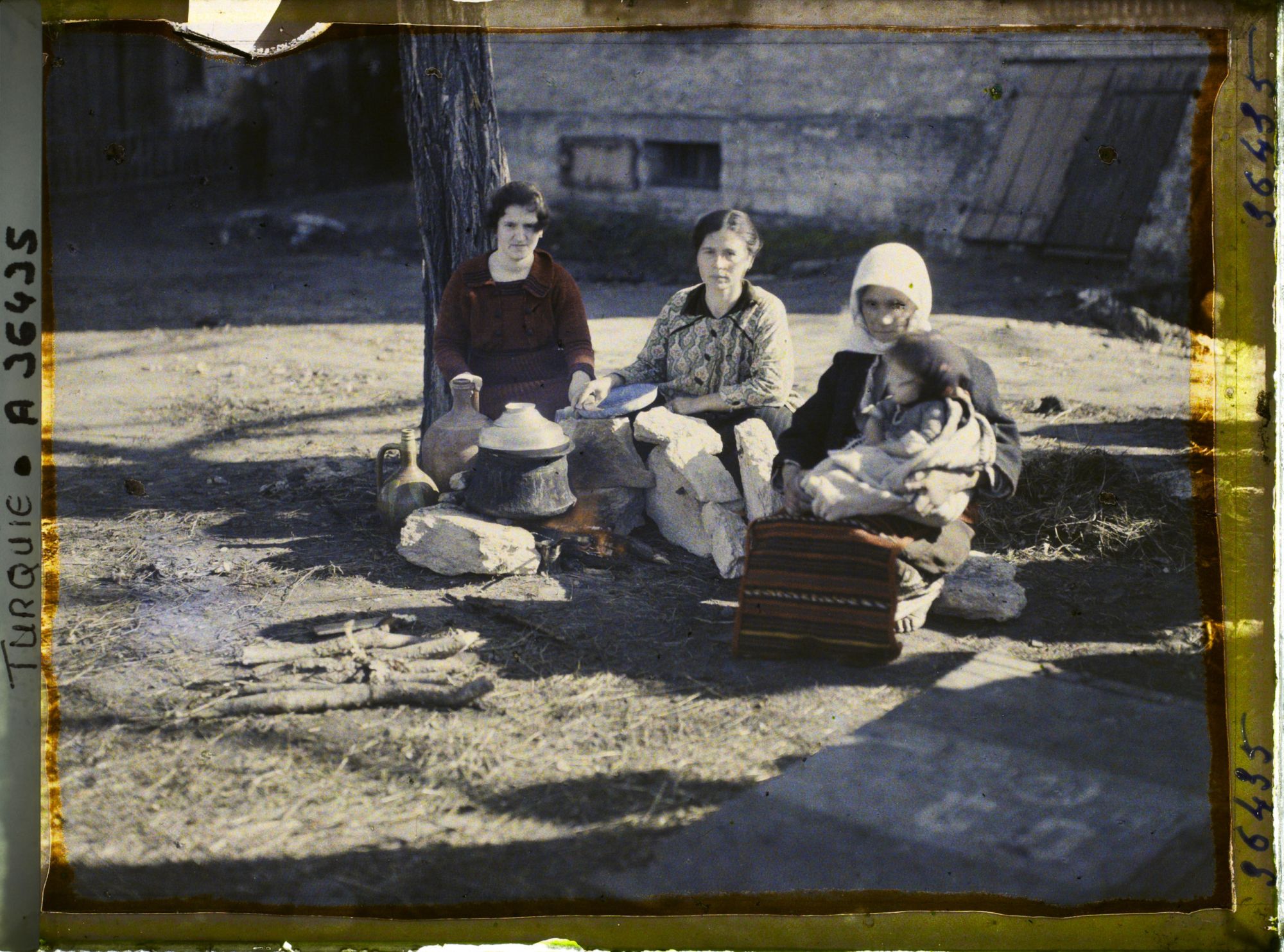 Image représentant Un groupe de femmes grecques dont l'une tenant un enfant près d'un foyer improvisé