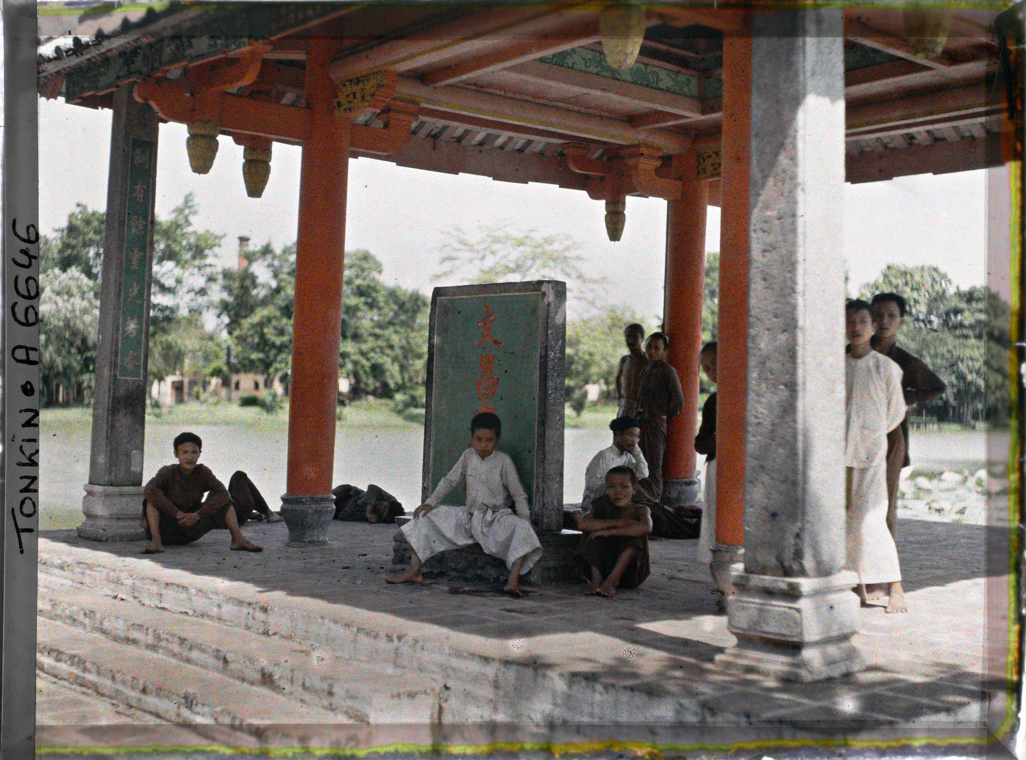Image représentant Un groupe d'enfants sous le Thui-toa " Kiosque du bord de l'eau ", abritant une stèle de pierre nommée " Tablette du Temple de Van-xu'o'ng "
