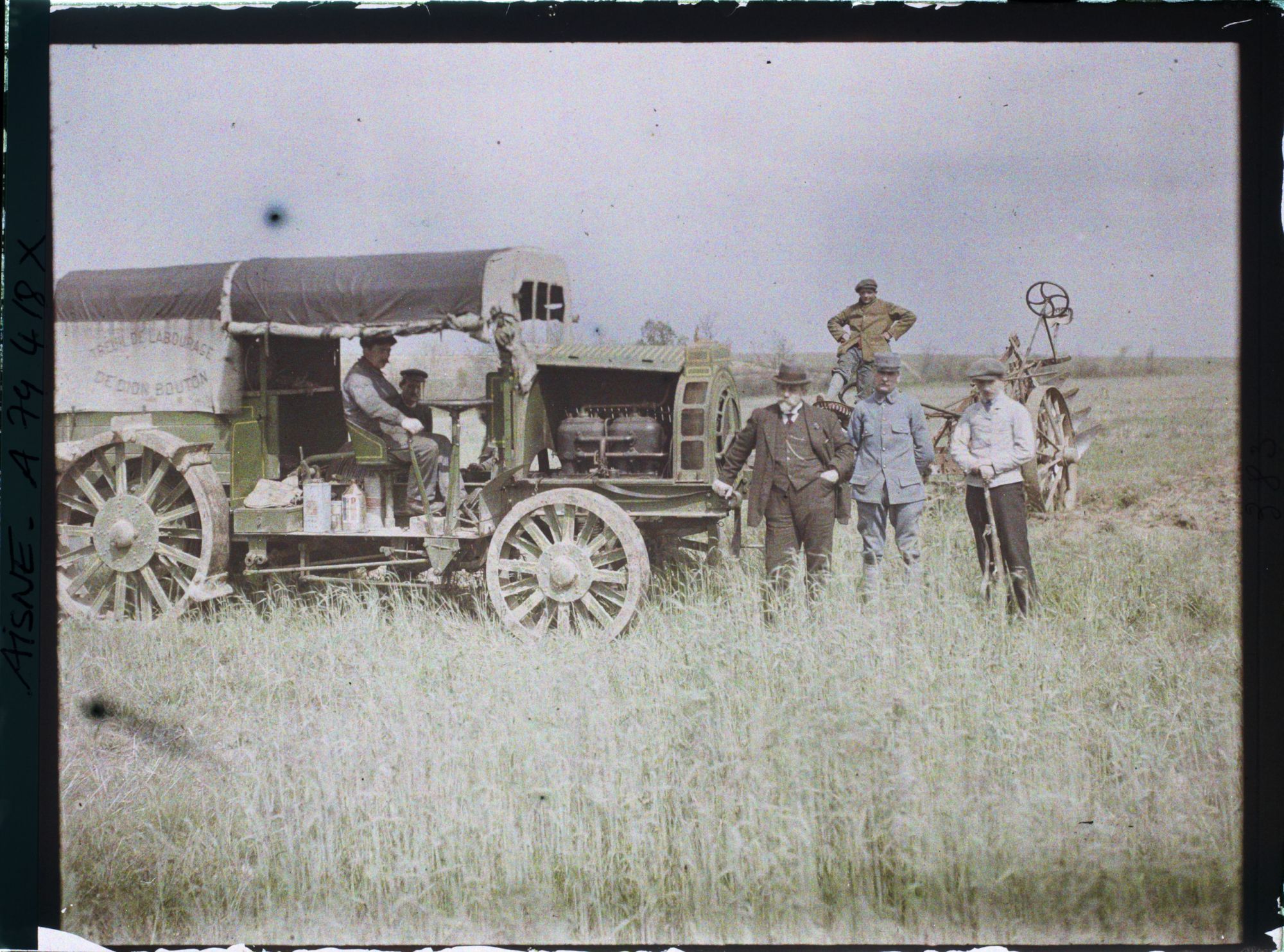 Image représentant Hommes prenant la pose aux côtés d'un camion destiné à tracter la charrue visible à l'arrière plan