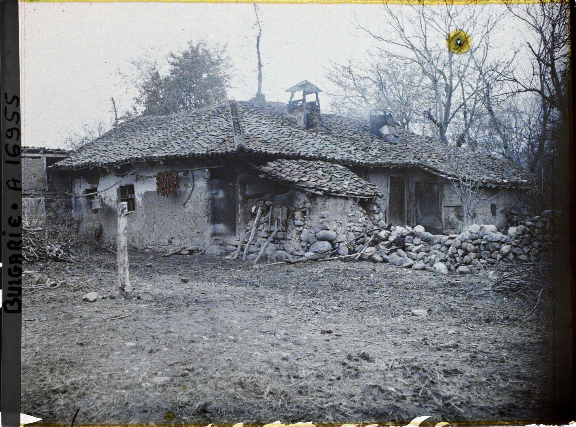 Image représentant Une ferme à toit de tuiles, murets en pierre et tas de petits bois