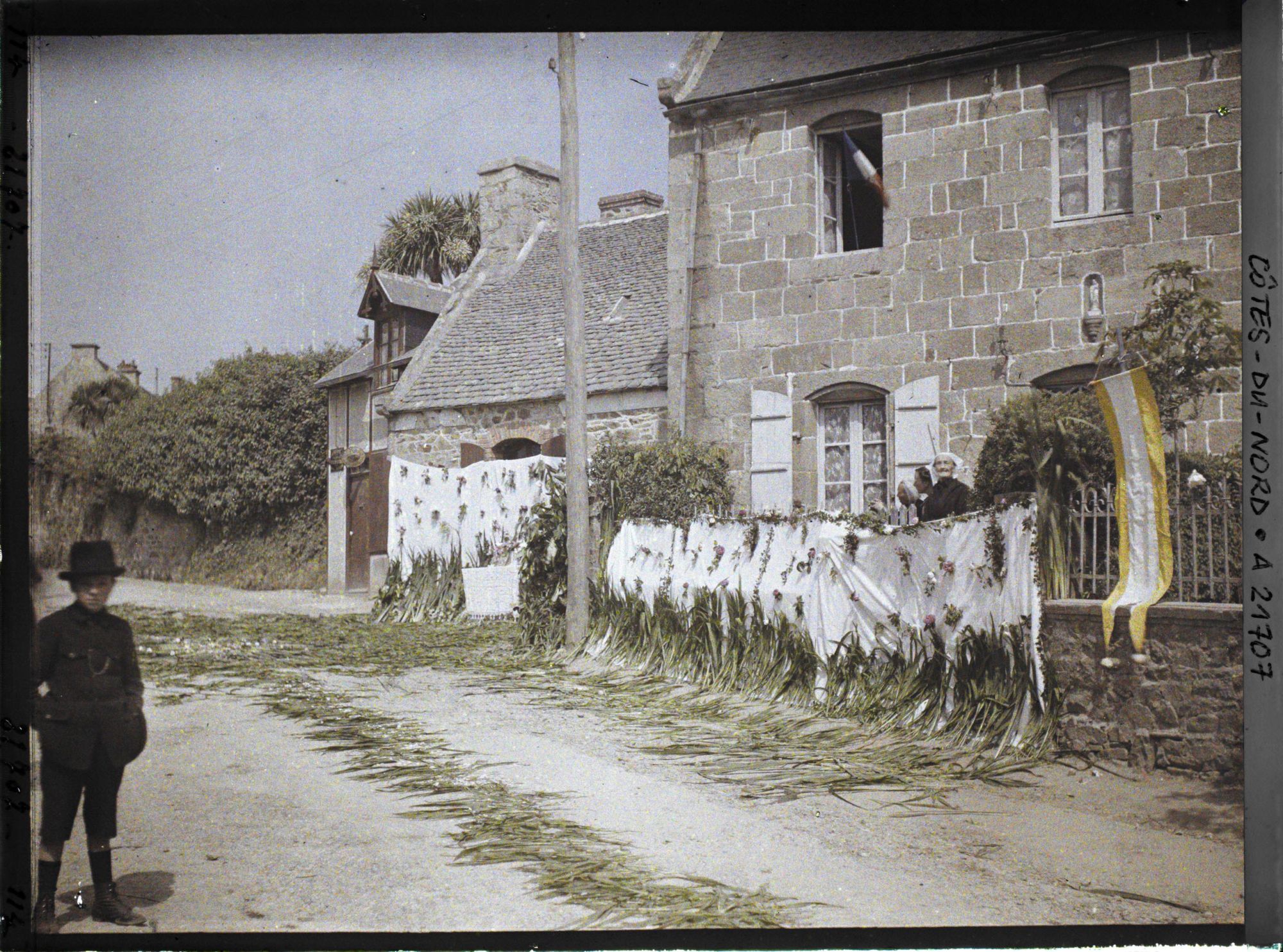 Image représentant La rue de l'Eglise (aujourd'hui rue du Maréchal Joffre) décorée pour la procession de la Fête-Dieu