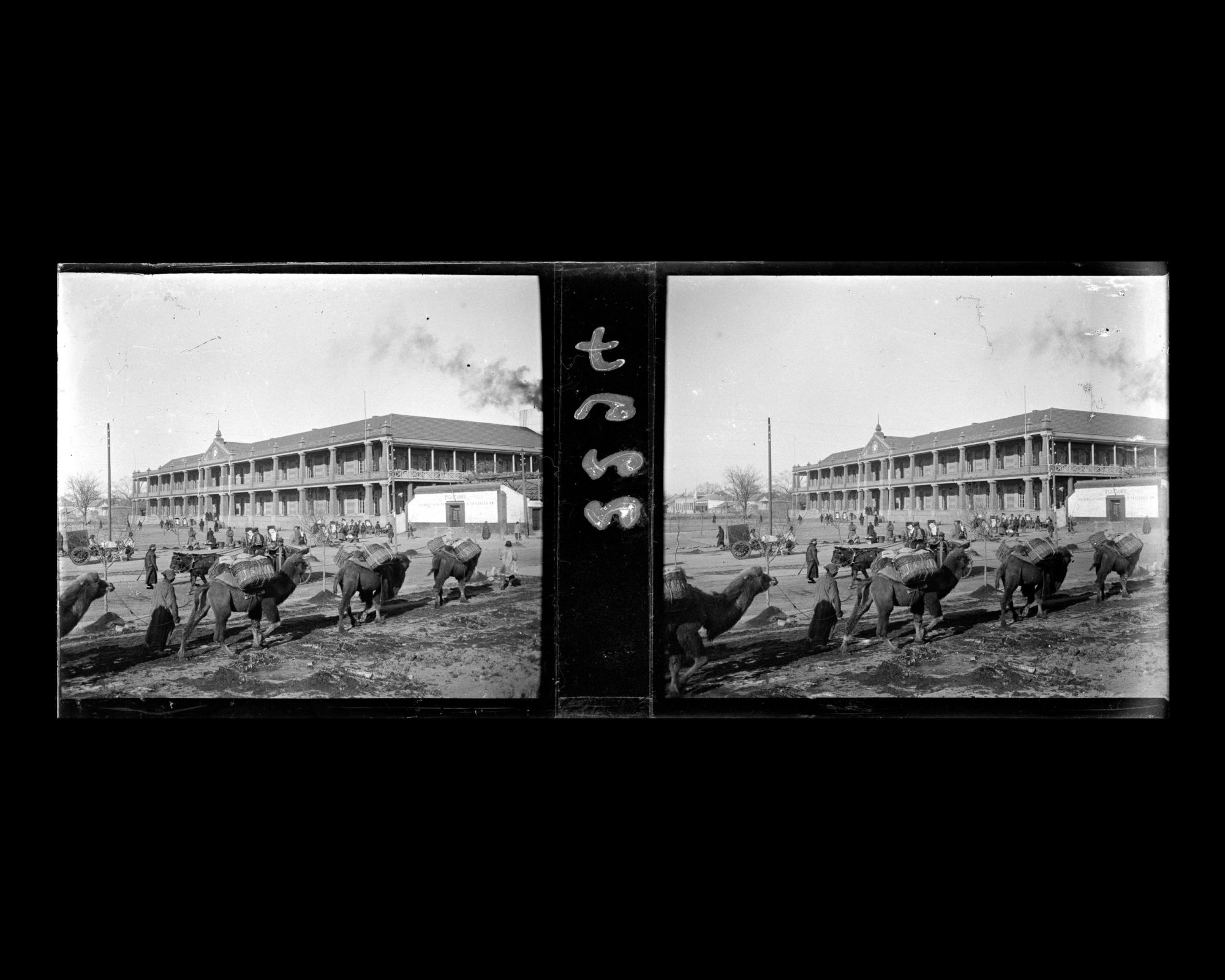 Image représentant Une caravane de chameaux de Bactriane sur Wangfujing dajie ("avenue du Puits des Résidences Princières") avec à l'arrière-plan le bâtiment de la ligne ferroviaire Pékin-Hankéou
