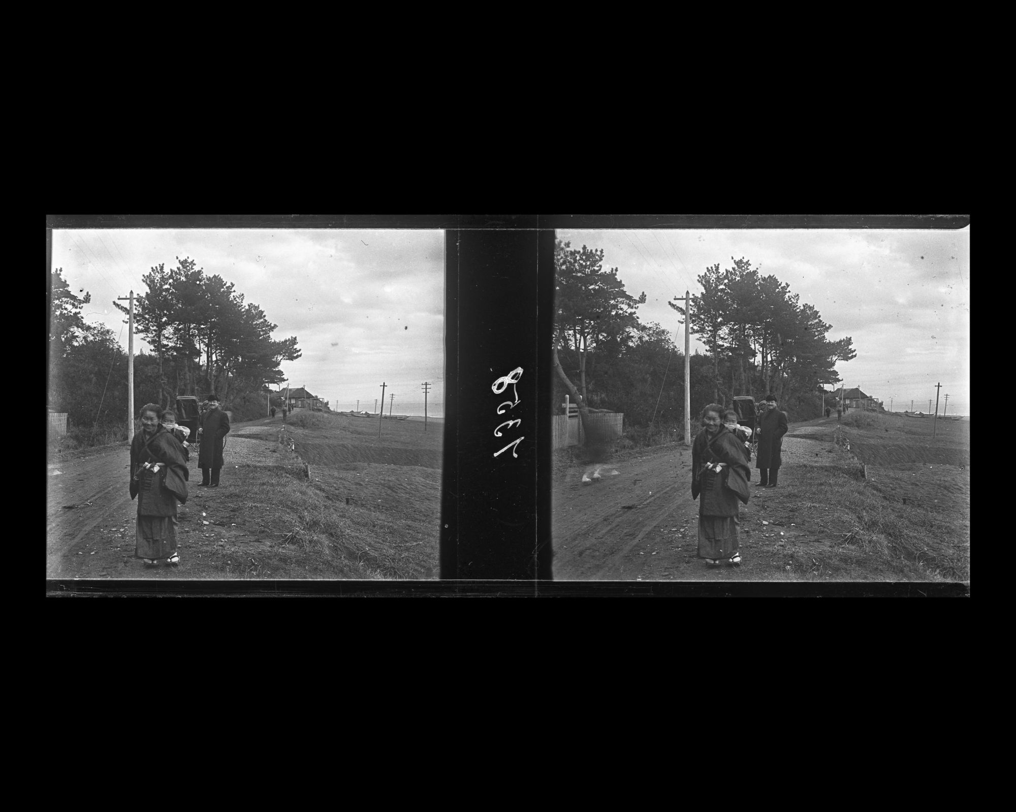 Image représentant Villageoise portant un enfant et un homme vêtu à l'occidentale sur la route qui longe la plage