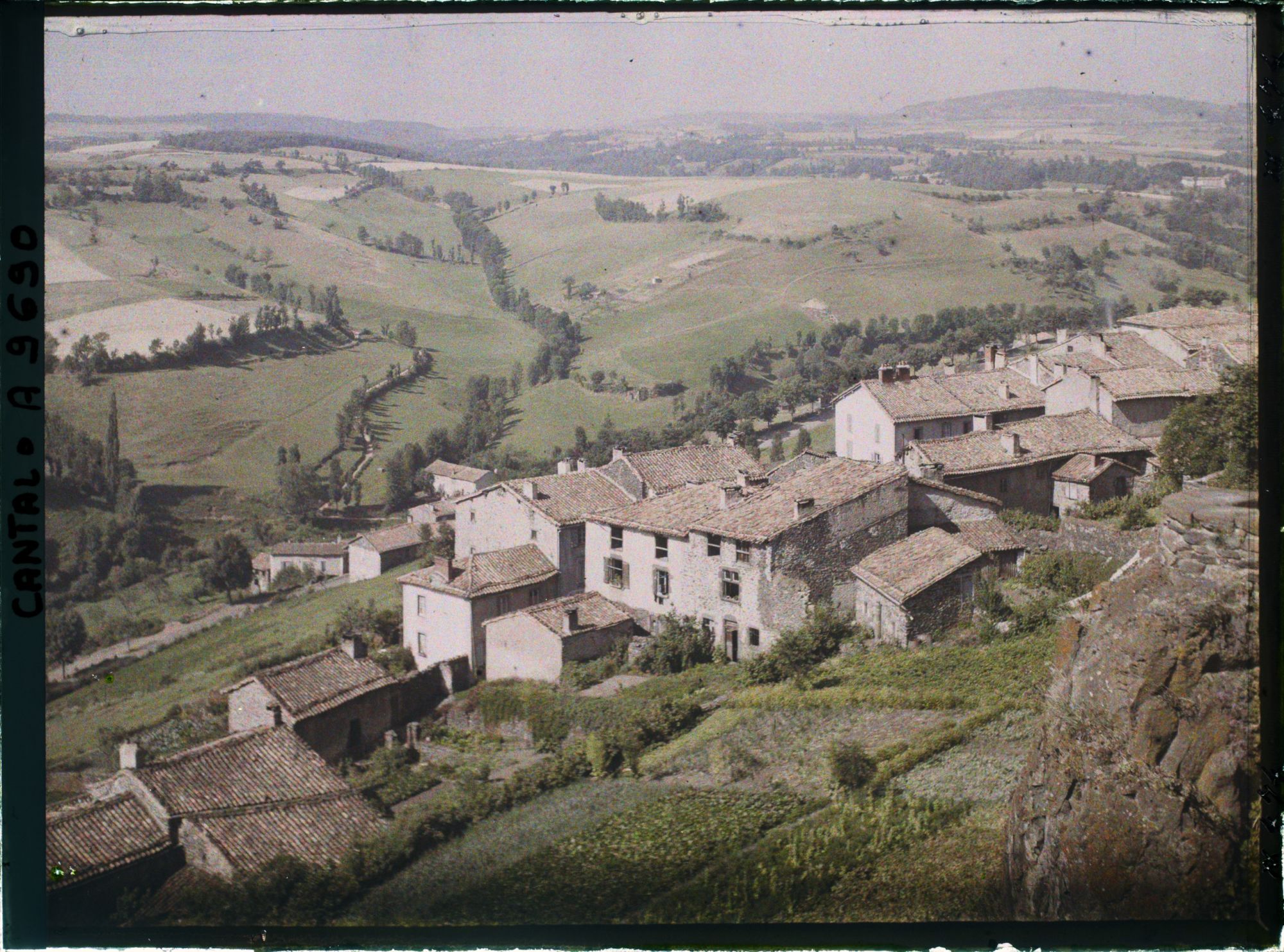 Image représentant Le Rocher de Saint Flour au premier plan et les maisons à toits plats de la rue descendante