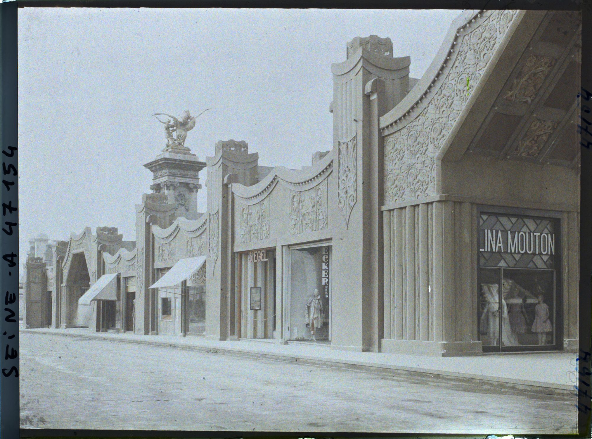 Image représentant L'Exposition des arts décoratifs, Rue des Boutiques sur le pont Alexandre III, Lina Mouton, couture, spécialité robes de jeunes filles