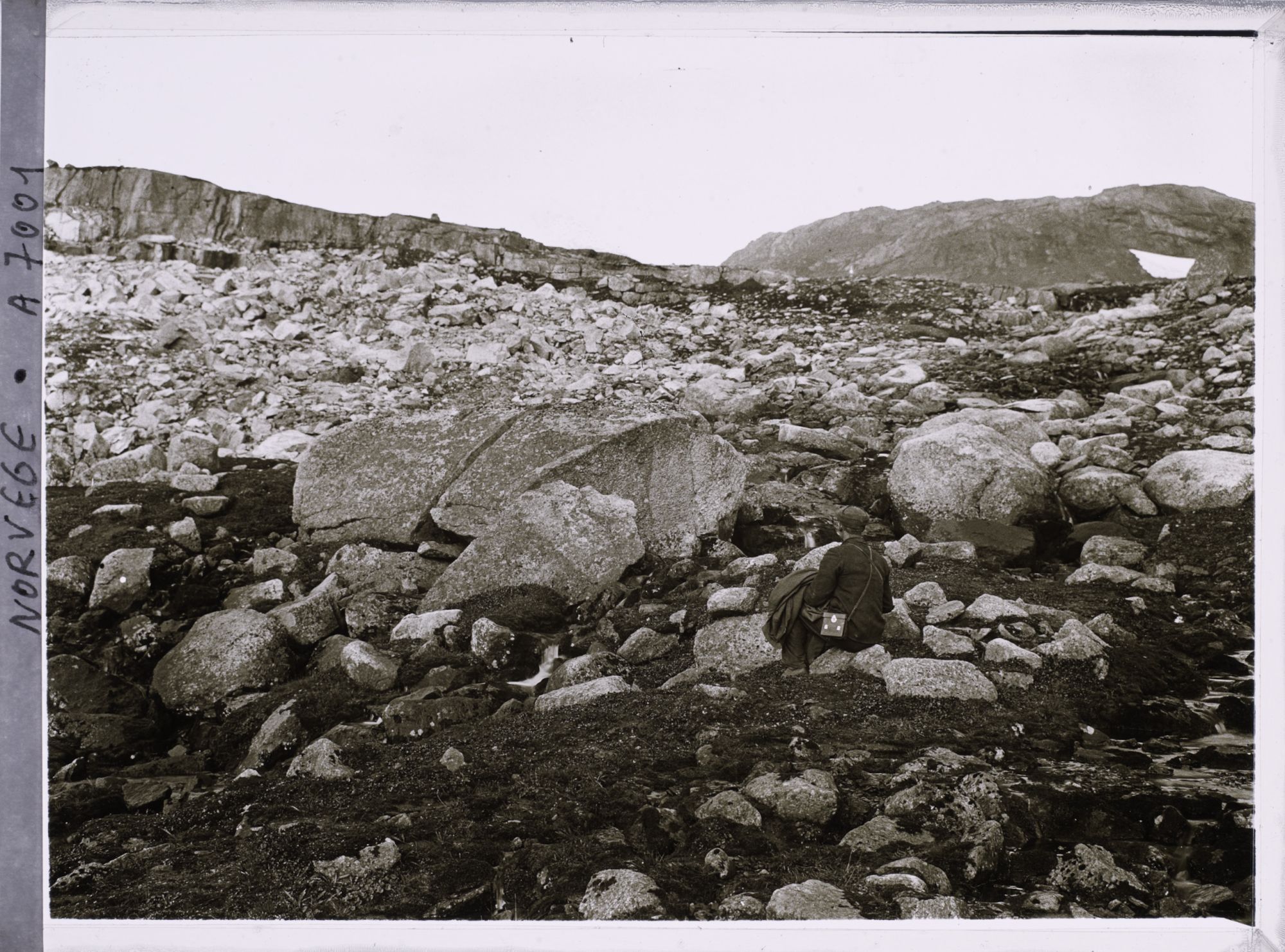 Image représentant L'aide de Wilse assis dans les éboulis près du glacier