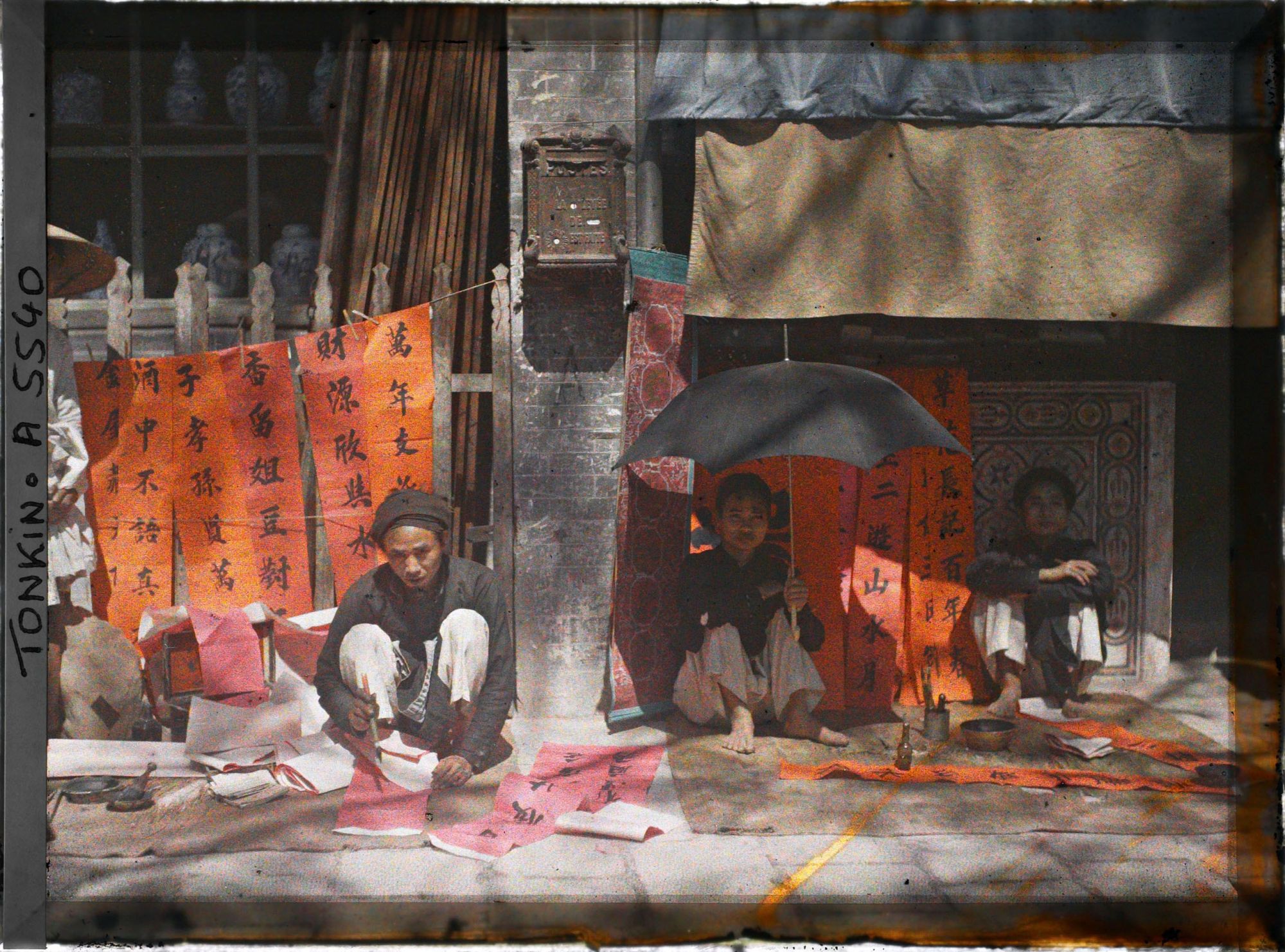 Image représentant Un artisan calligraphiant des " sentences parallèles " en vente à l'époque de la fête du Têt