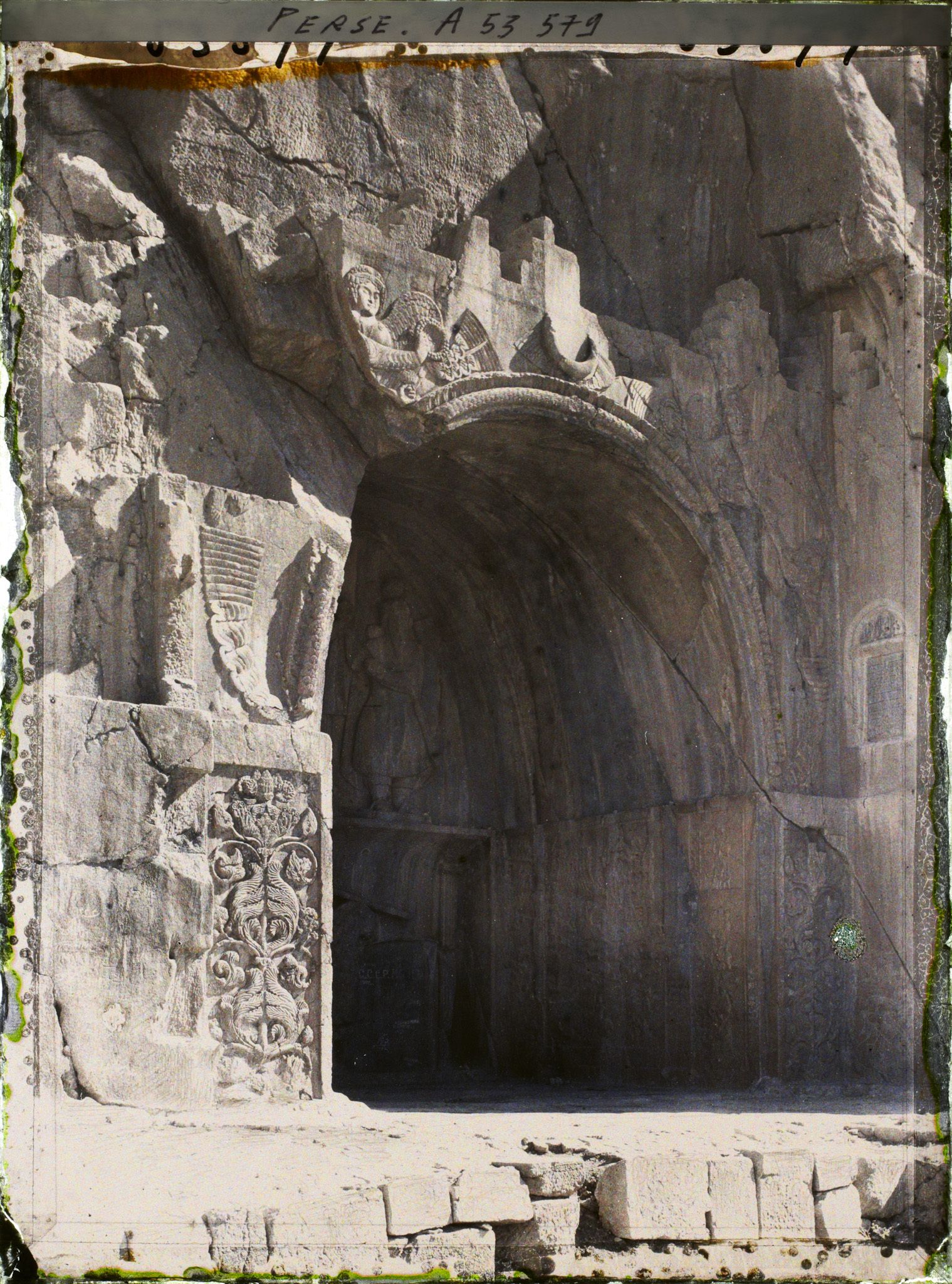 Image représentant La grande grotte, celle de Khosro II. Au-dessus de la voûte, figure ailée d'inspiration romaine portant l'anneau du pouvoir et le diadème royal