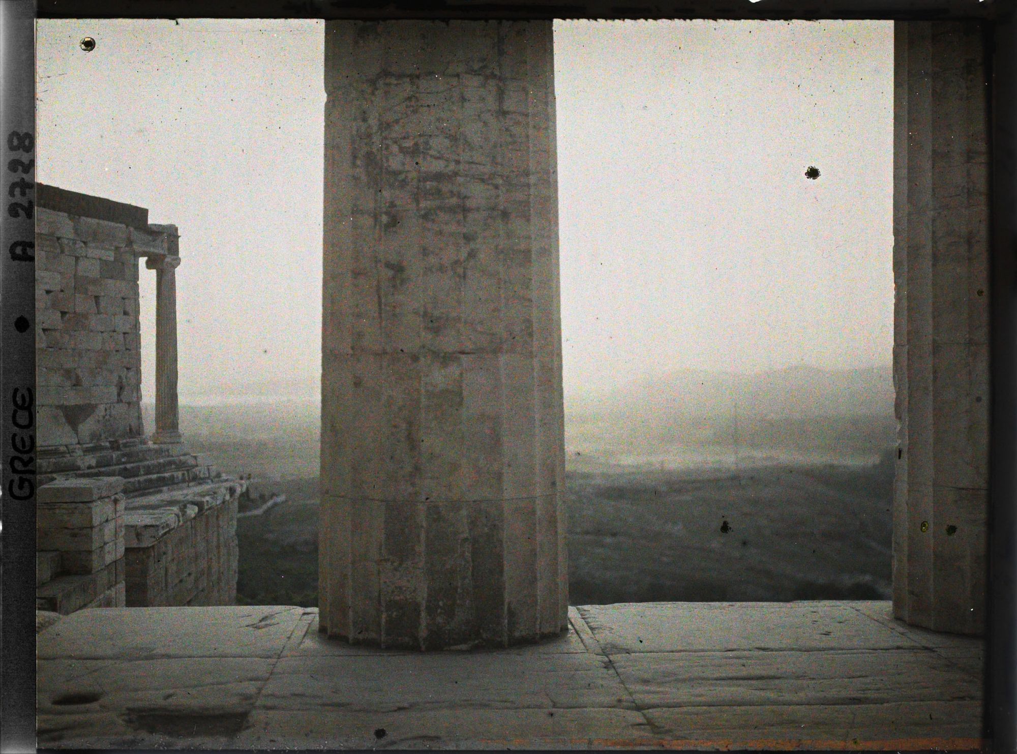 Image représentant Sur l'Acropole, au premier plan, une colonne de Propylées de Mnesicles et au fond, le Temple d'Athéna Nike, les environs et la mer