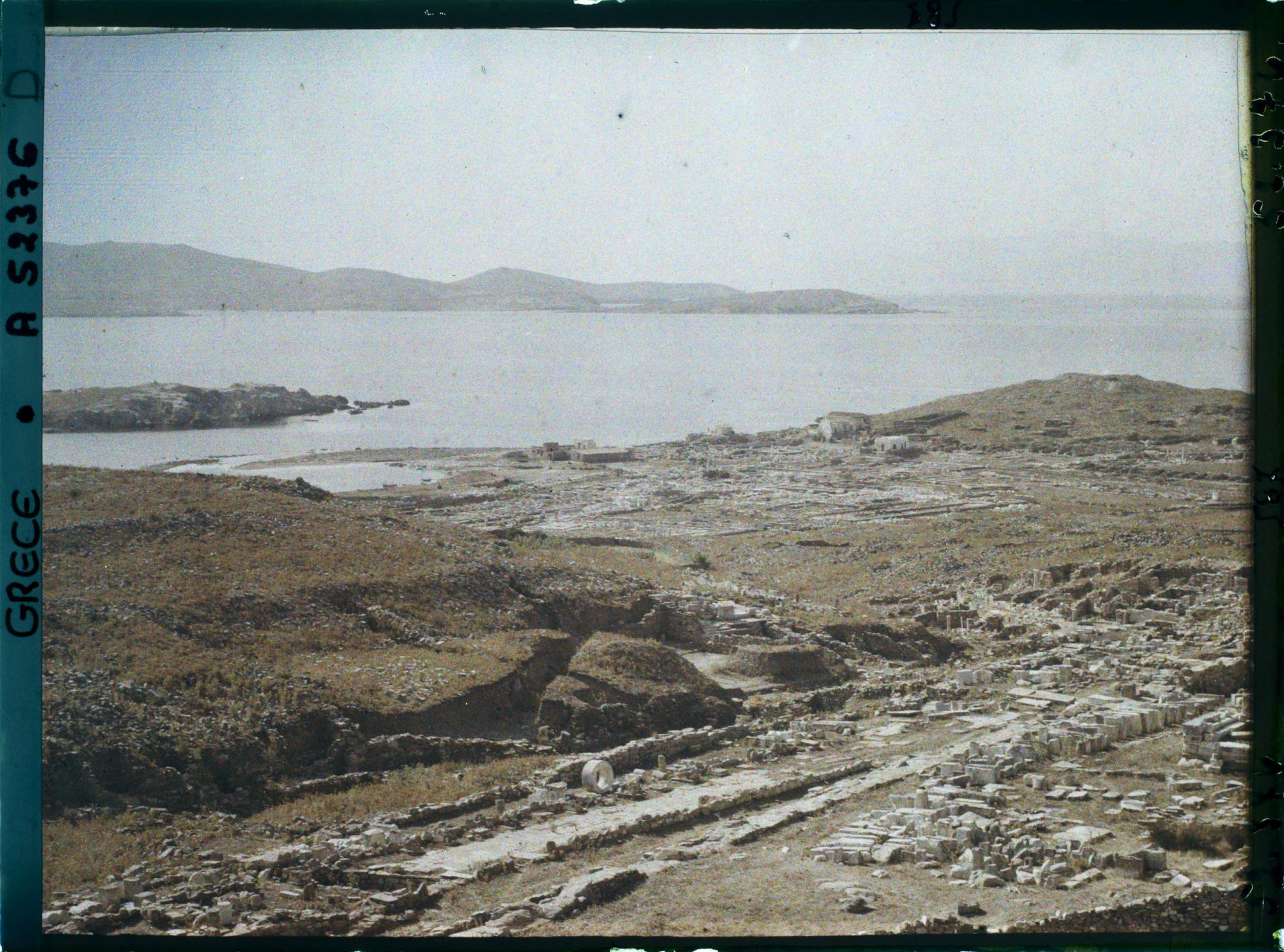 Image représentant Panorama vers les ruines de la ville antique (haute et basse) et la mer depuis l'Antre du Cinthe sur le versant occidental du mont Cinthe (au fond, l'Ile de Syros)