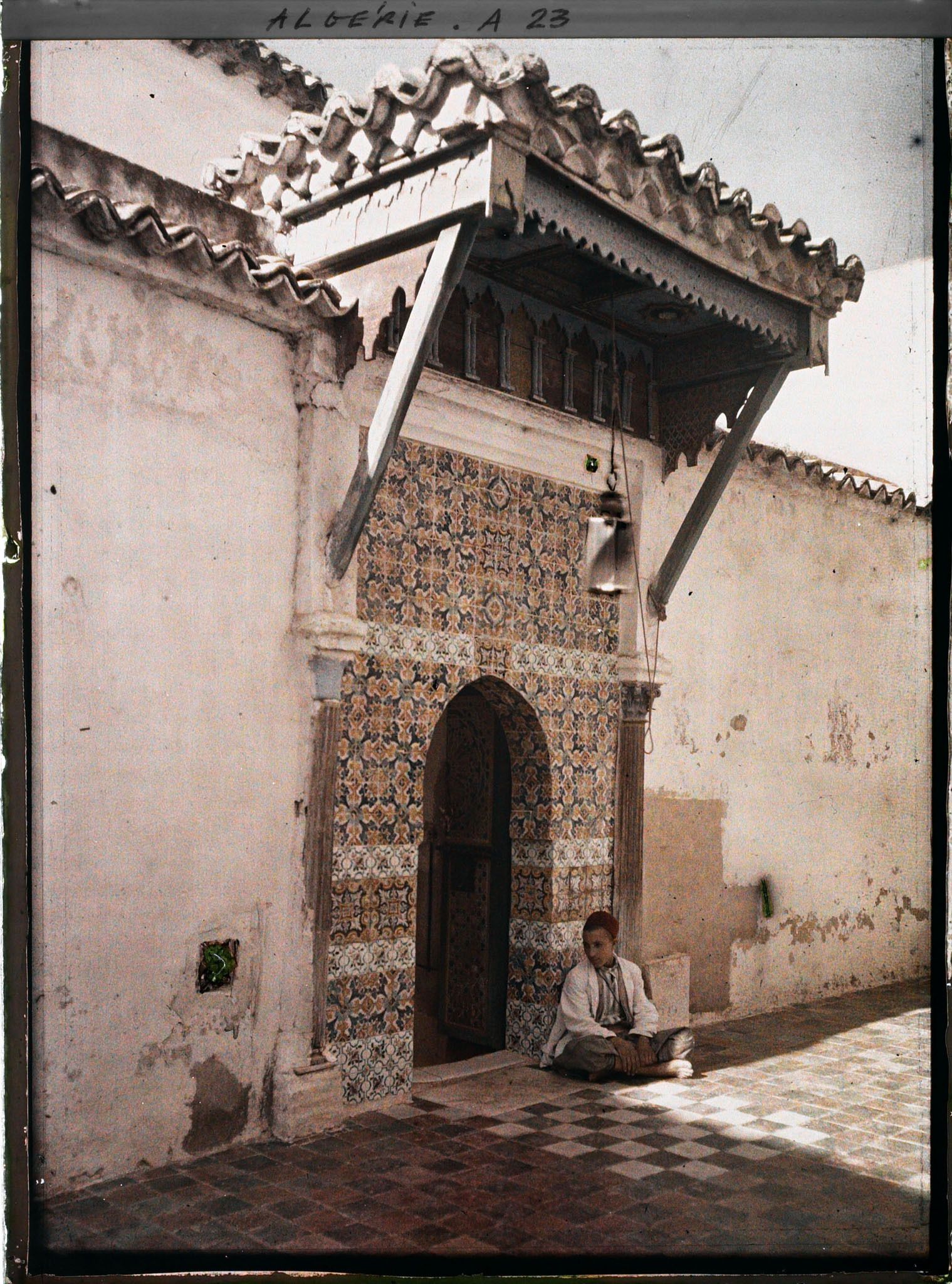 Image représentant Un adolescent assis sur le pas de la porte de la  null koubba de Sidi bou Médine