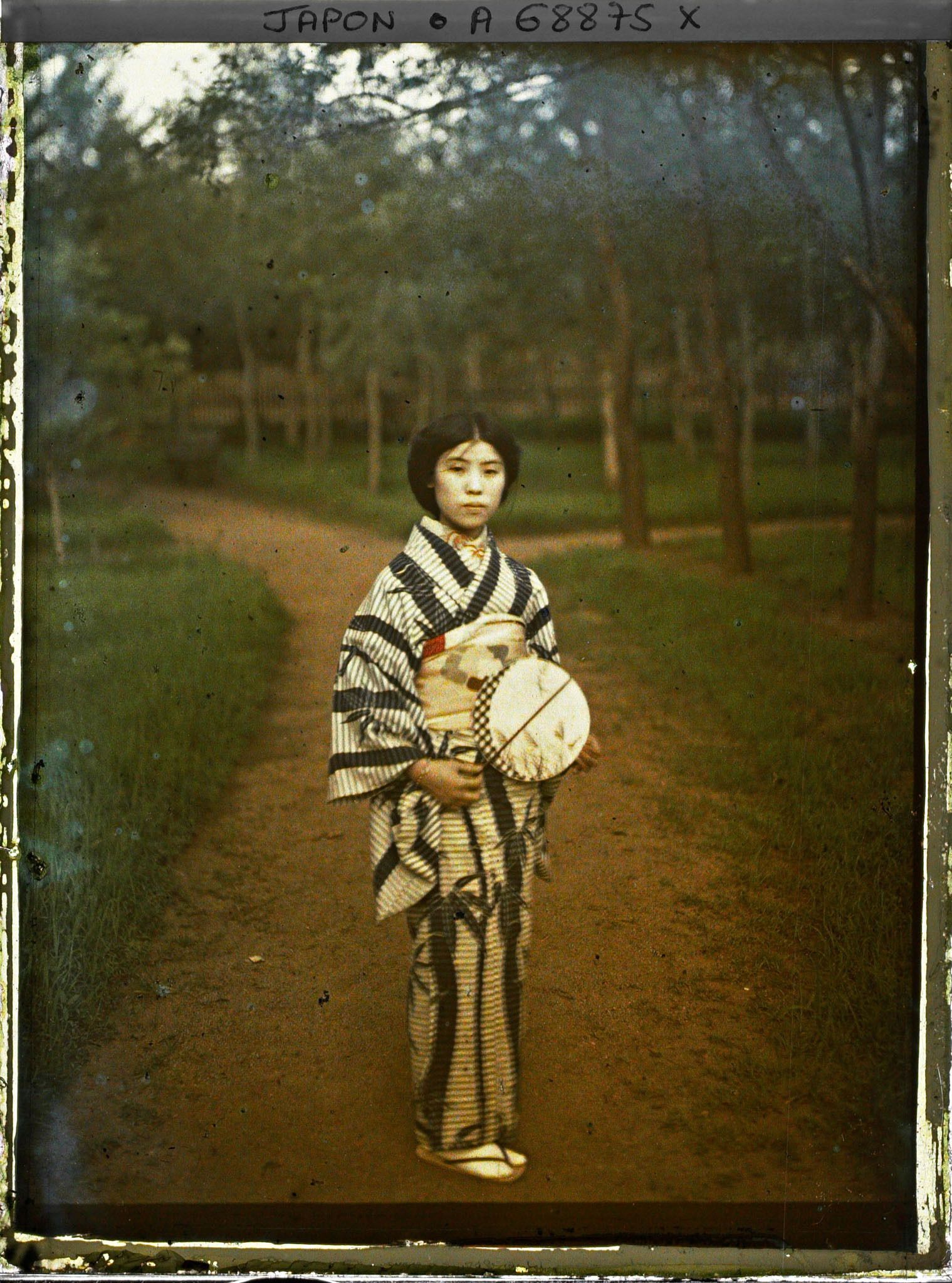 Image représentant jeune fille en kimono avec un éventail dans un jardin