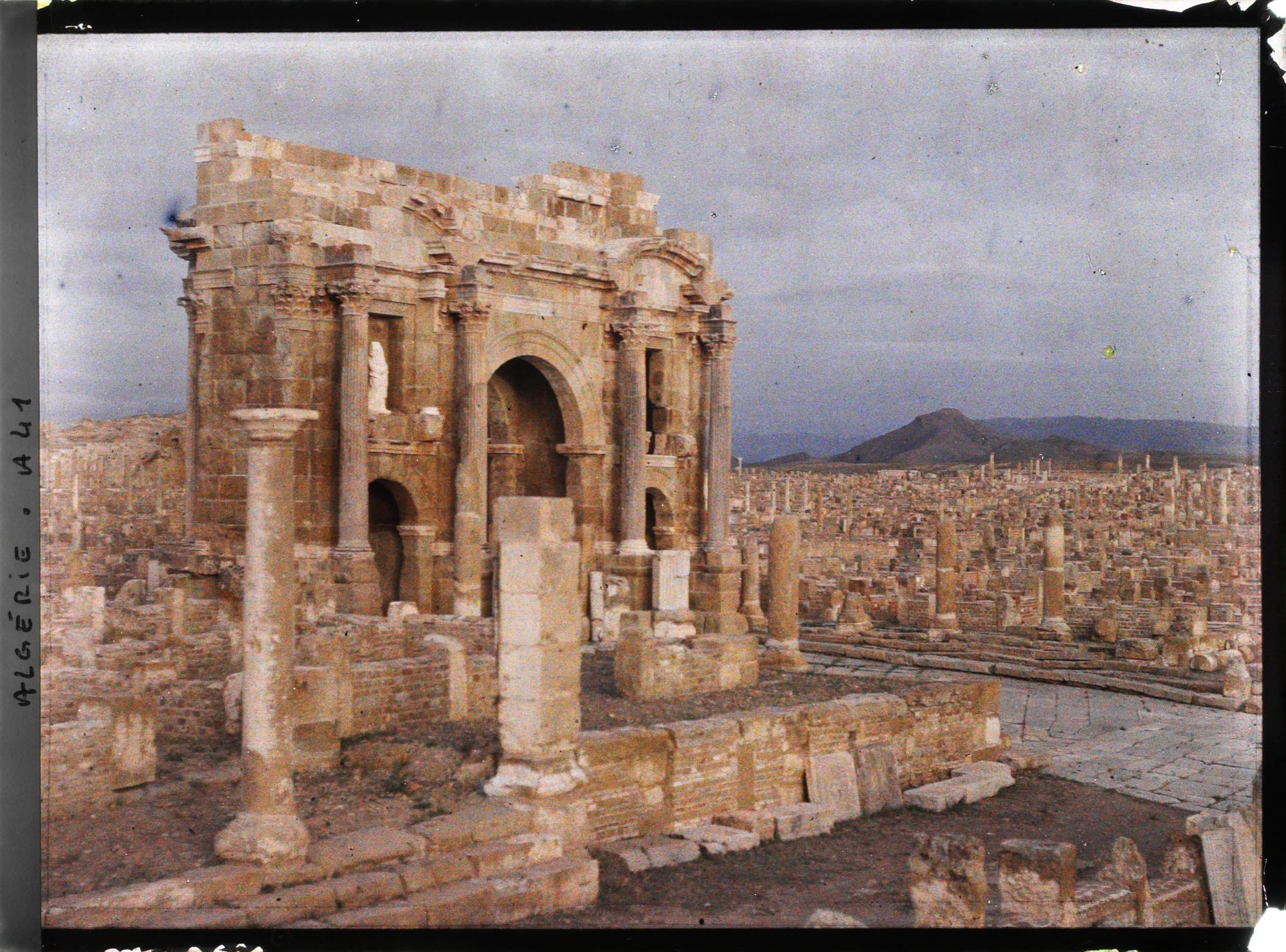 Image représentant L'arc de Trajan vu depuis le temple du Génie de la colonie