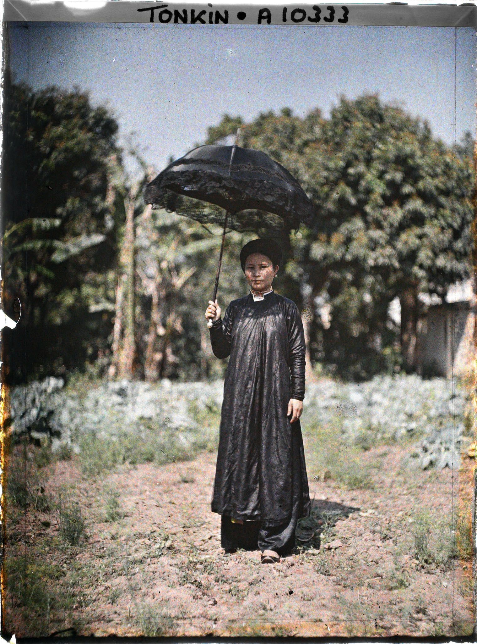 Image représentant Une femme de classe aisée, s'abritant sous une ombrelle noire bordée de dentelle