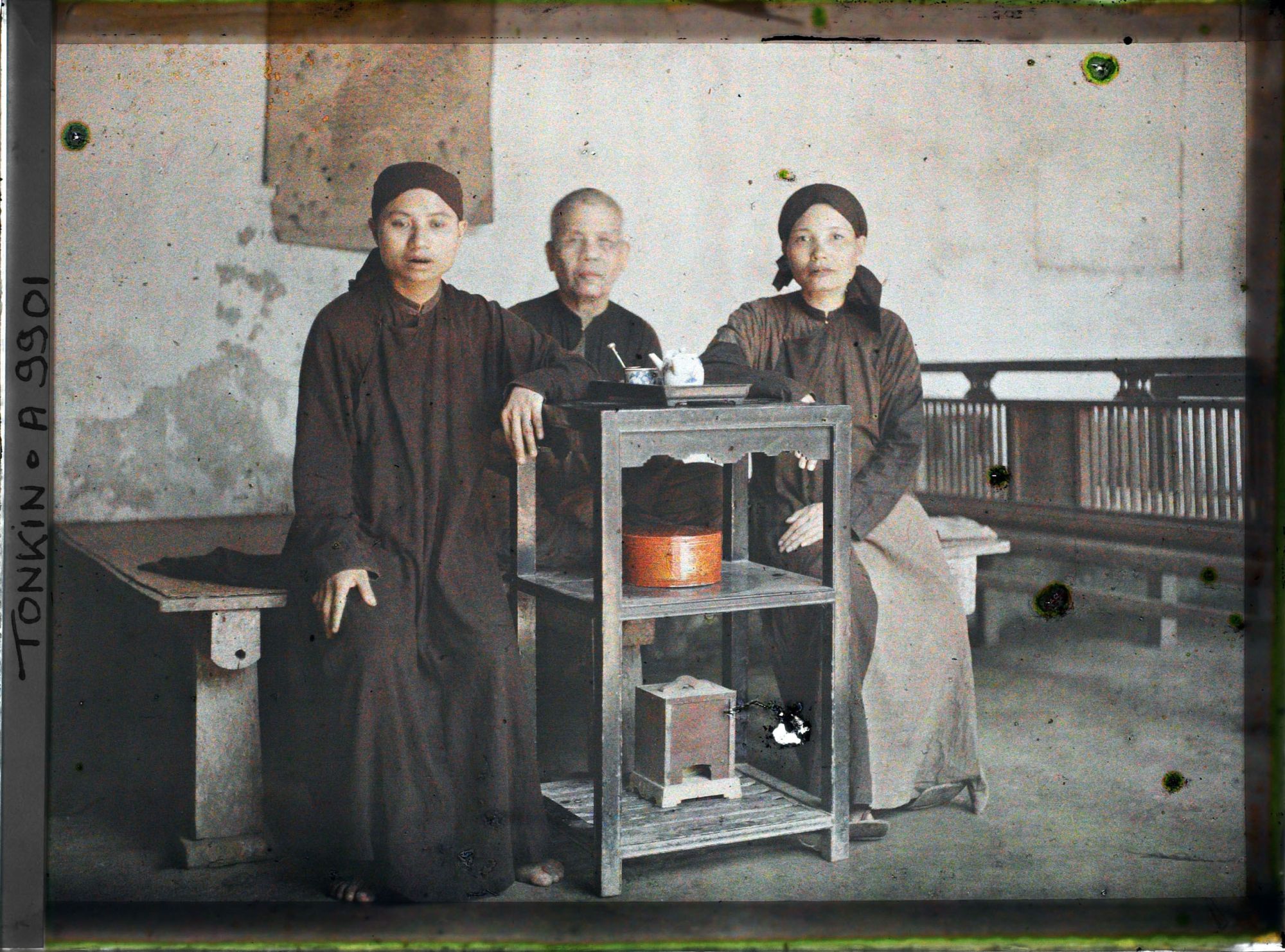 Image représentant Une bonzesse et deux novices assises près d'une desserte supportant un service à thé