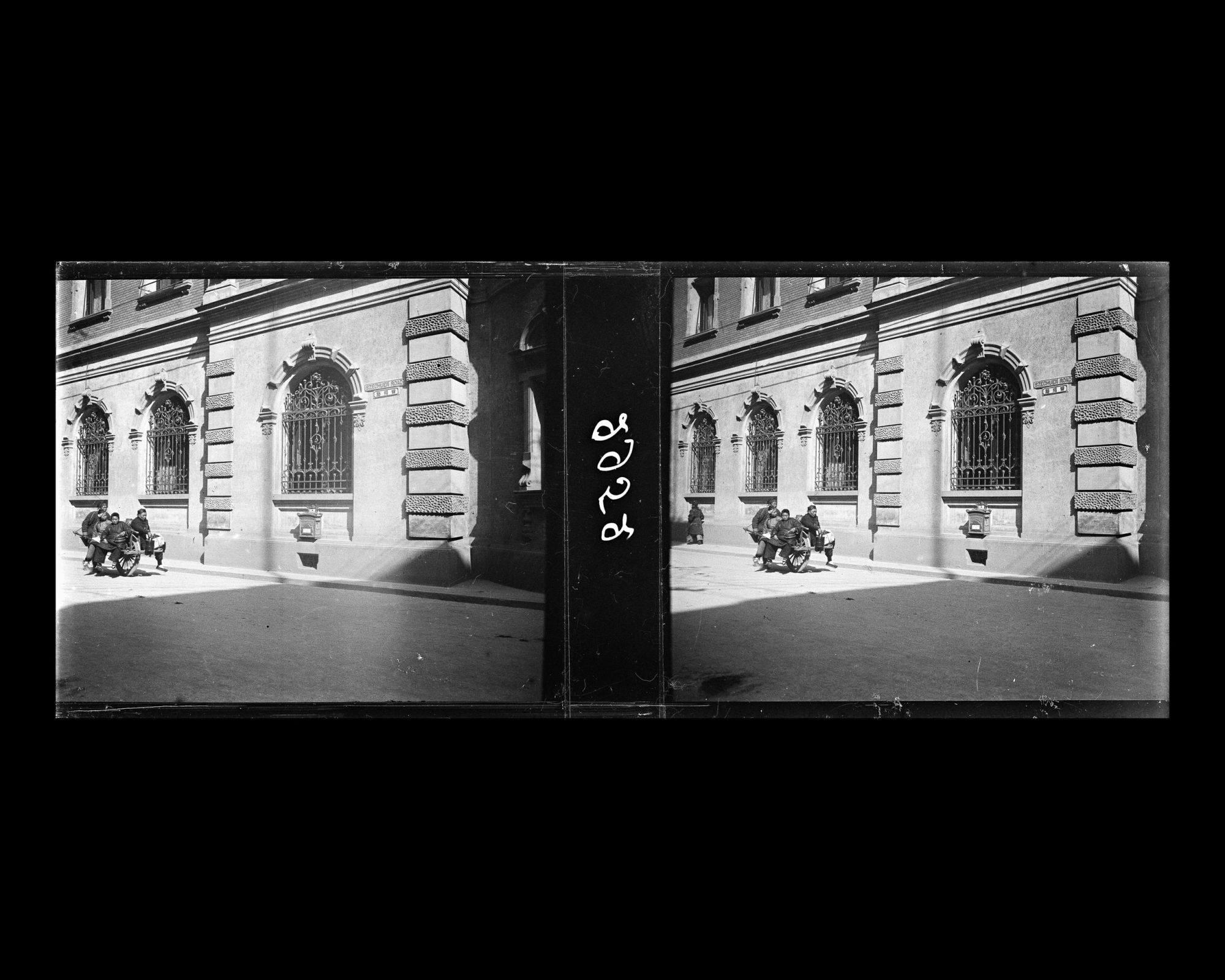 Image représentant Sichuan Road, actuelle Sichuanlu ("rue du Sichuan"), dans la Concession internationale. Un porteur avec une brouette à roue unique, devant la façade du bâtiment de la poste allemande (Shuxinguan).