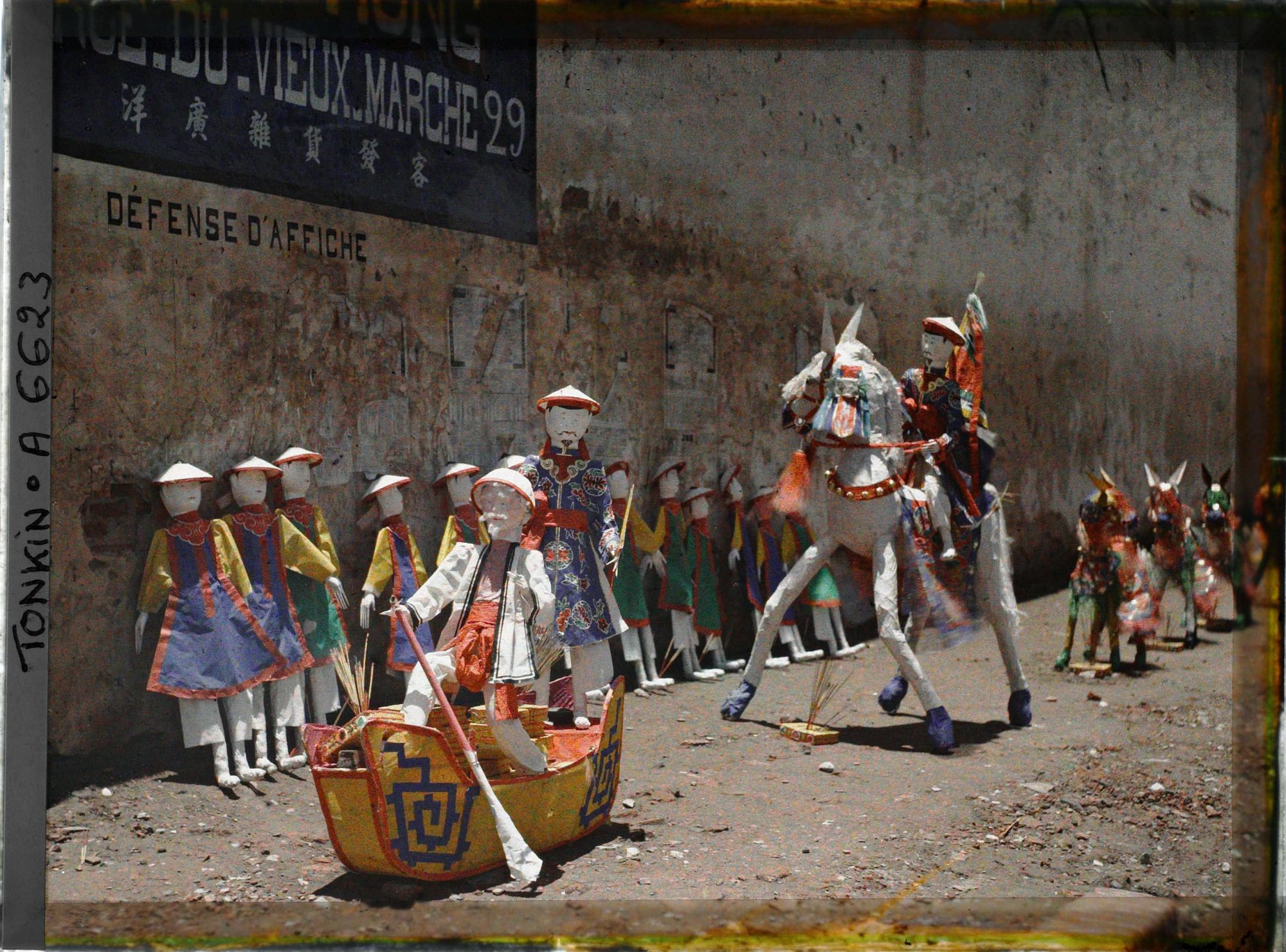 Image représentant Une exposition d'objets votifs en papier (barque, cavalier, personnages...), à l'angle de la " rue du Vieux Marché " et de la " rue des Médicaments "