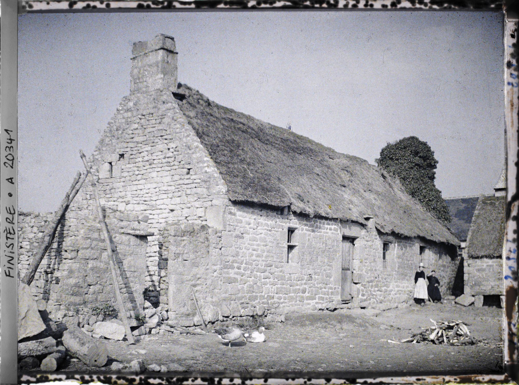 Image représentant Deux femmes devant un bâtiment de ferme couvert de chaume