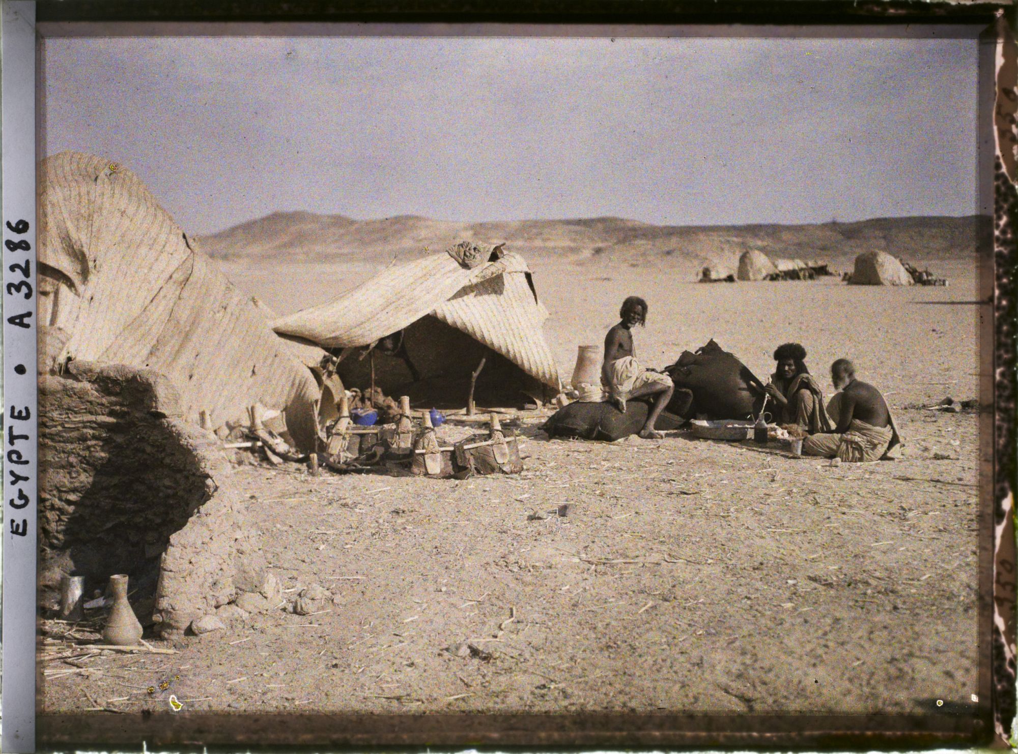 Image représentant Trois hommes  null bishari assis devant leurs habitations
