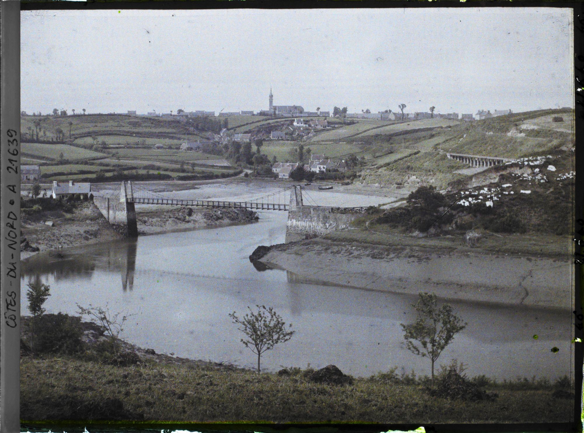 Image représentant La passerelle Saint-François sur le Guindy ; à l'arrière-plan, le village de Plouguiel