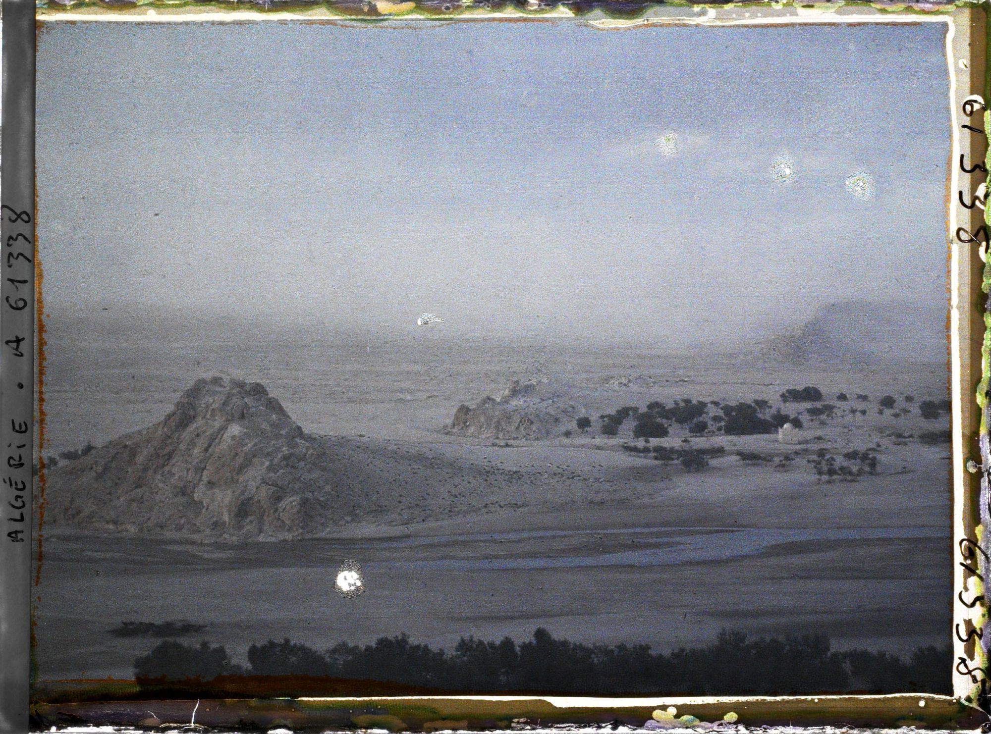 Image représentant Le lit de l'Oued Mzi avec à l'arrière-plan une tempête de sable