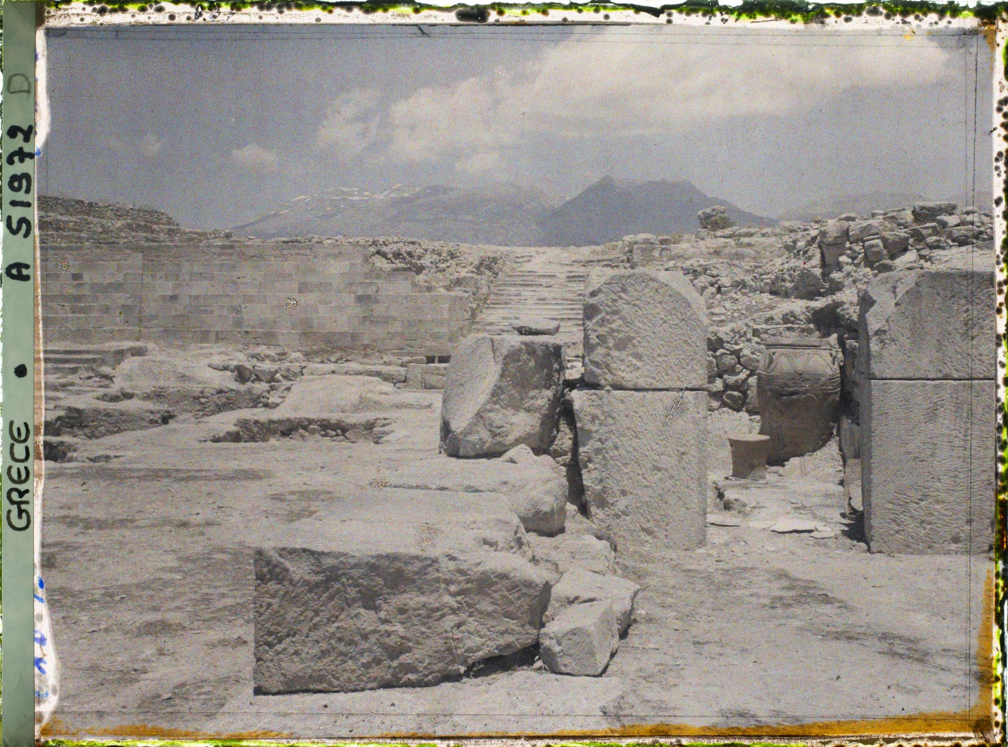 Image représentant Le palais. Dans la cour occidentale, au fond, l'escalier nord. En premier plan, à droite, extrémité des magasins avec un phitos (jarre)