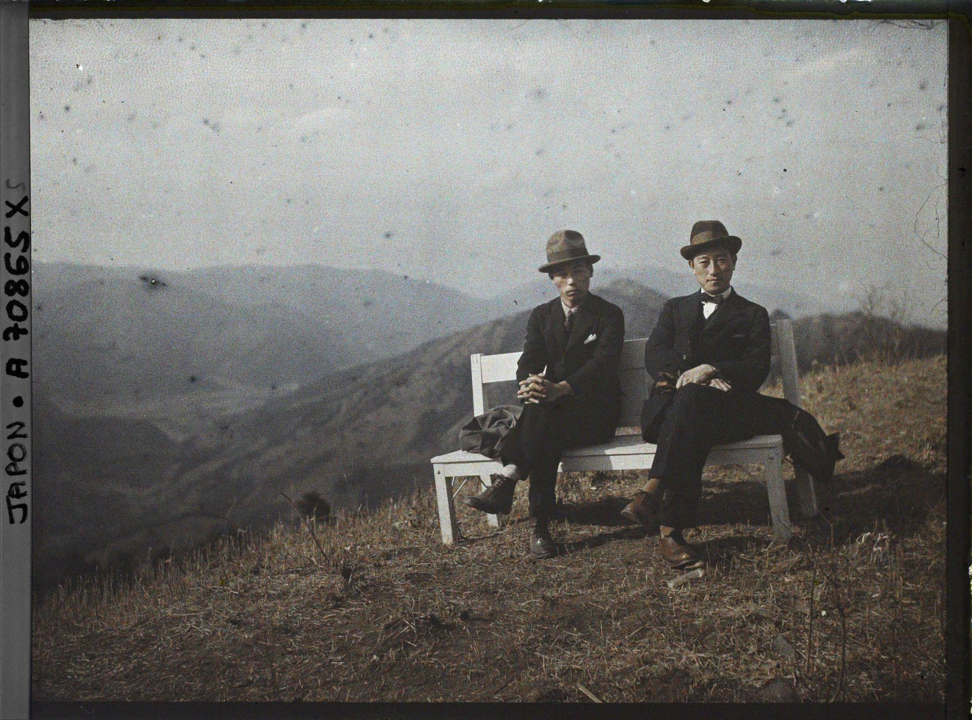 Image représentant Mont Hiei : Deux hommes sur un banc devant la vue vers la vallée d'Ohara et Yase