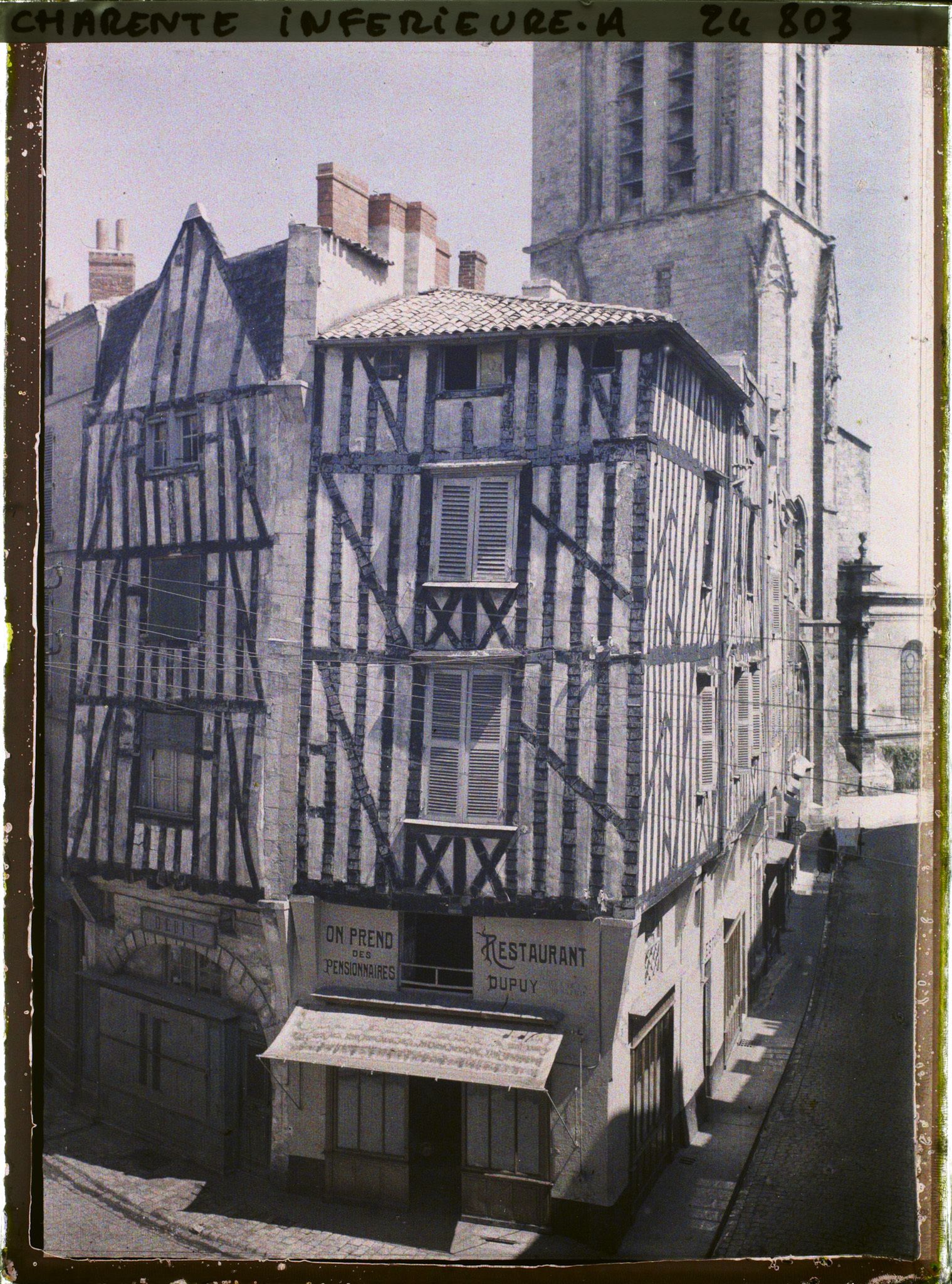 Image représentant Maison à colombages, le restaurant Dupuy à l'angle de la rue de la Bletterie et la rue Saint-Sauveur, au fond l'église Saint-Sauveur