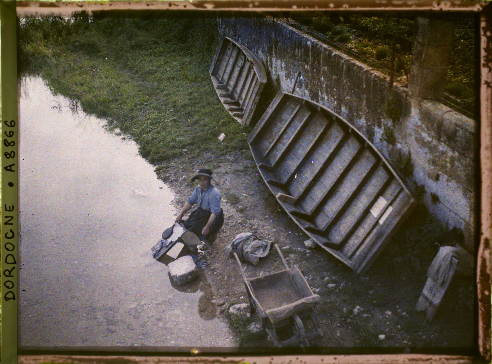 Image représentant Jeune femme lavant son linge au bord de la Dronne, des barques plates derrière elle