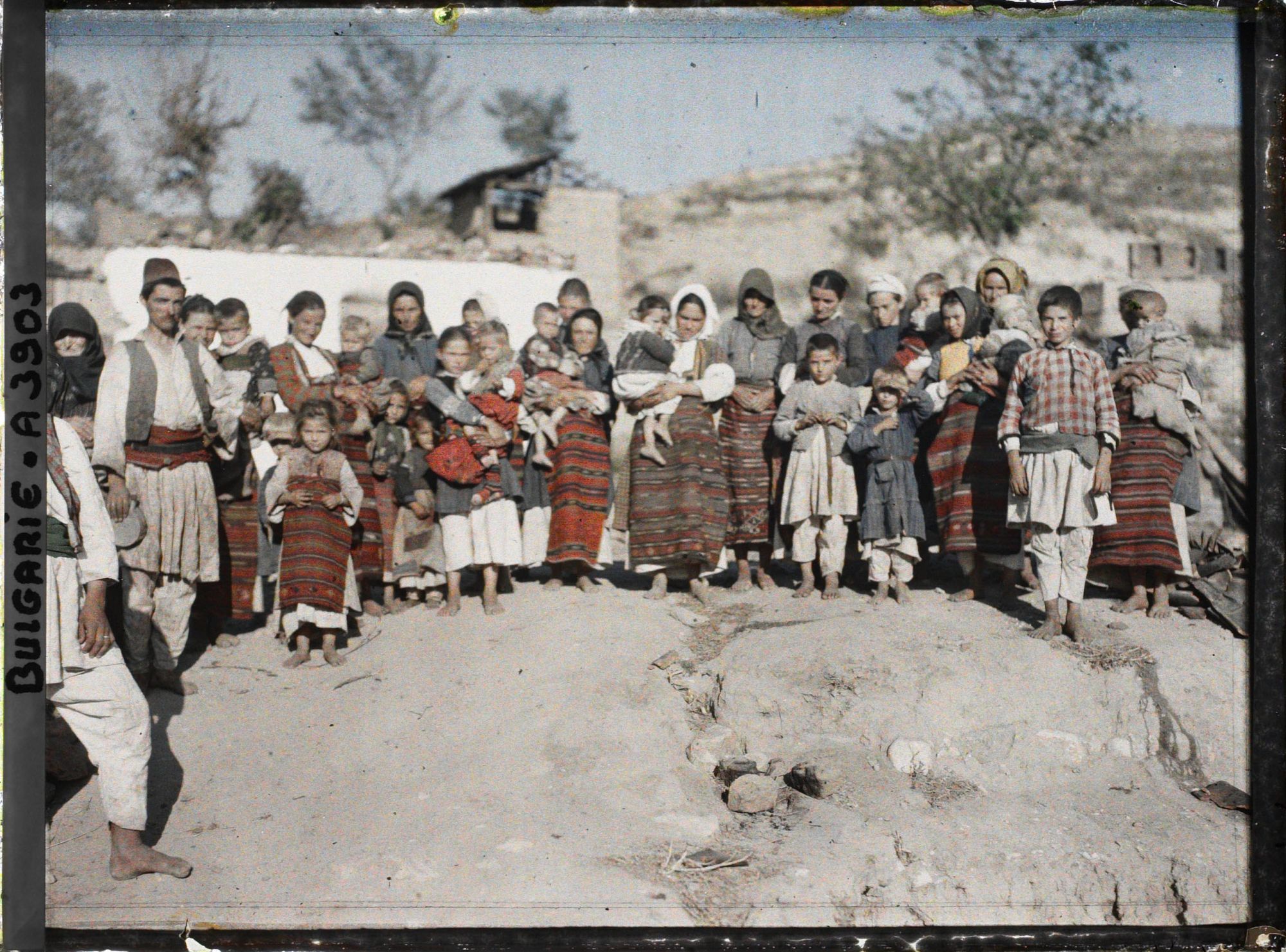 Image représentant Groupe d'habitants et femmes à tabliers tissés devant les décombres de leur village
