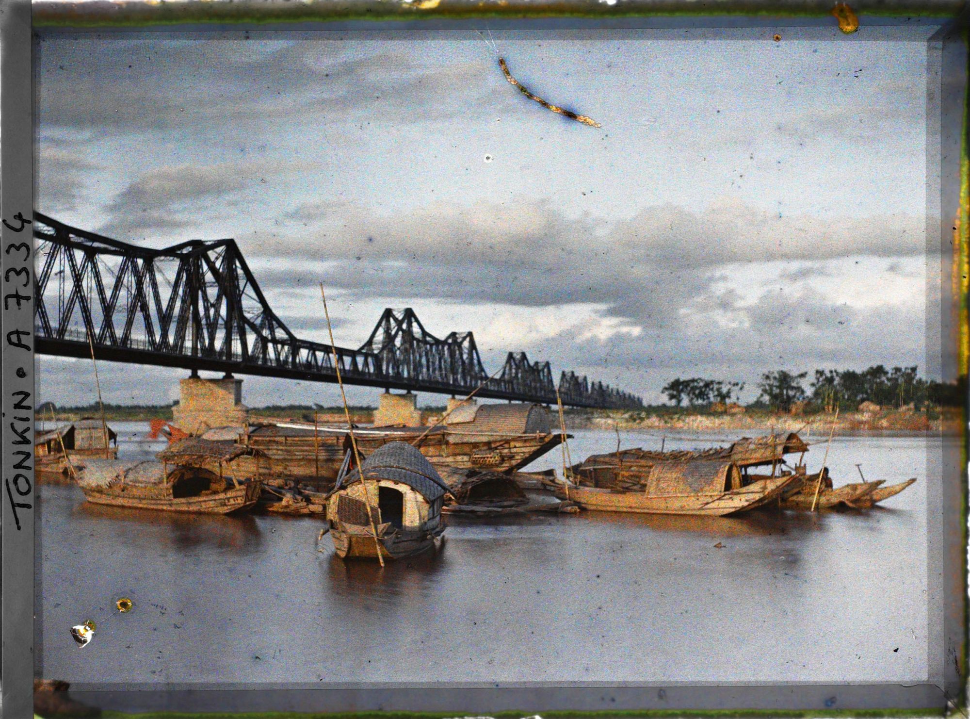 Image représentant Des sampans au soleil couchant sur le Fleuve Rouge devant le pont Doumer